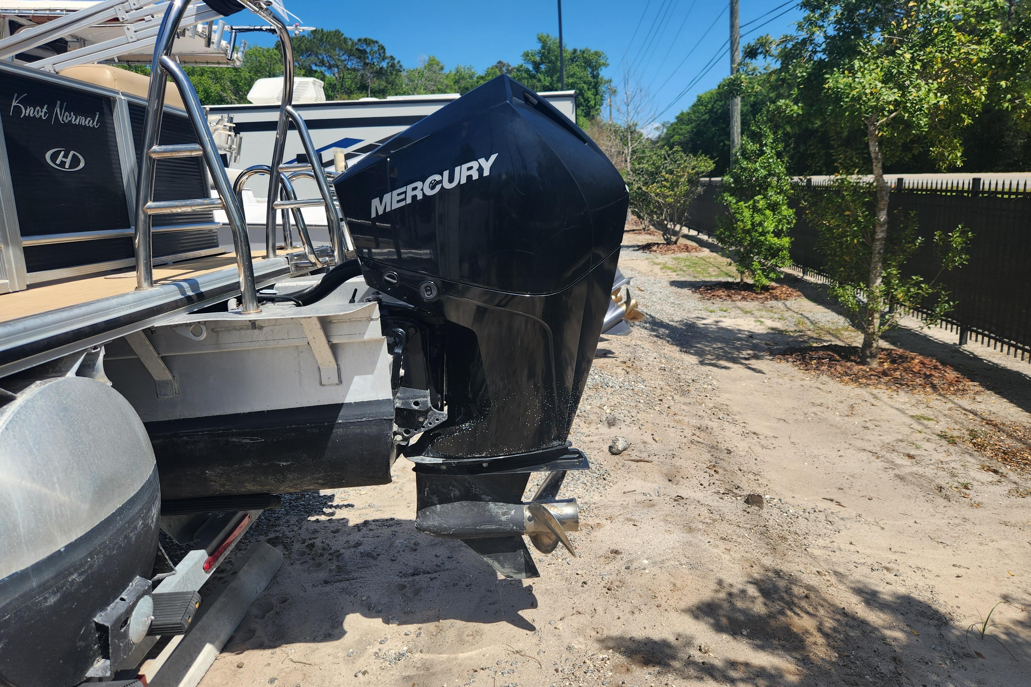 2019 Harris Sunliner 250 boat with Mercury outboard motor on a sandy path.