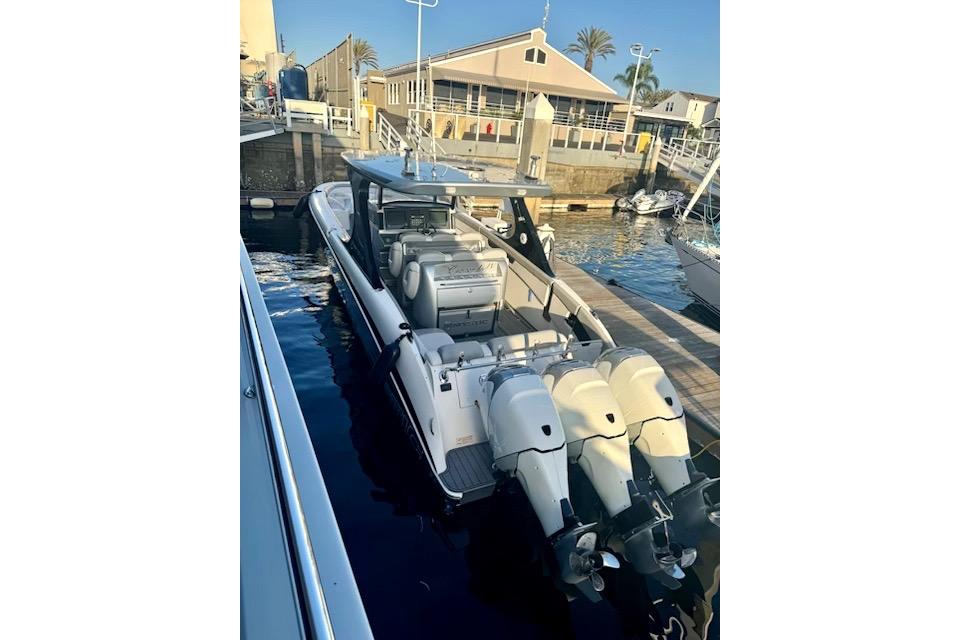 2016 Mystic M4200 boat docked with triple outboard engines.