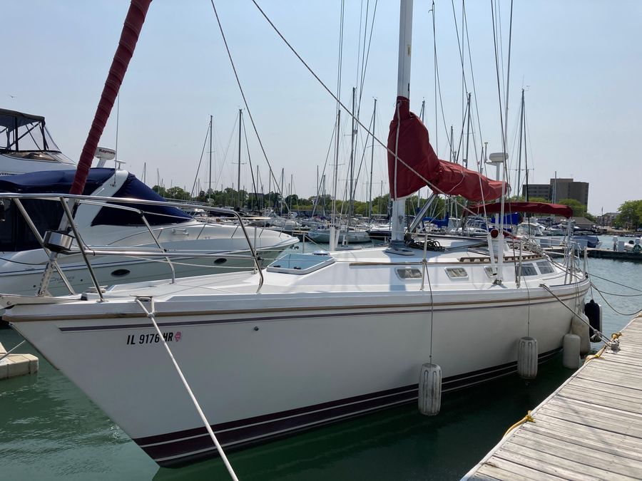 A 1990 Catalina 42 Tricabin docked at a marina. Other boats are visible in the background.