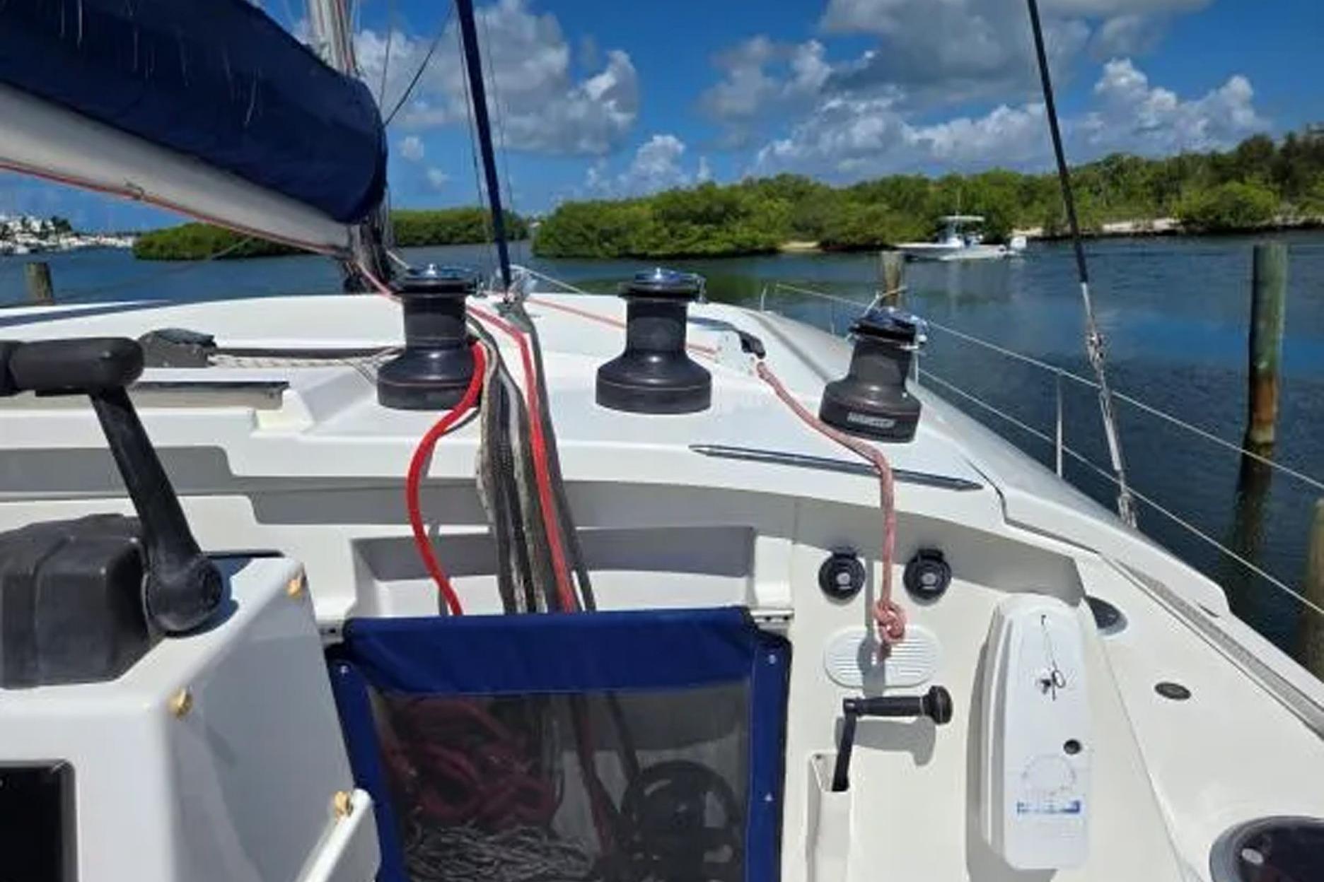 2008 Fountaine Pajot Salina 48 sailboat cockpit with winches and ropes, docked by lush greenery.