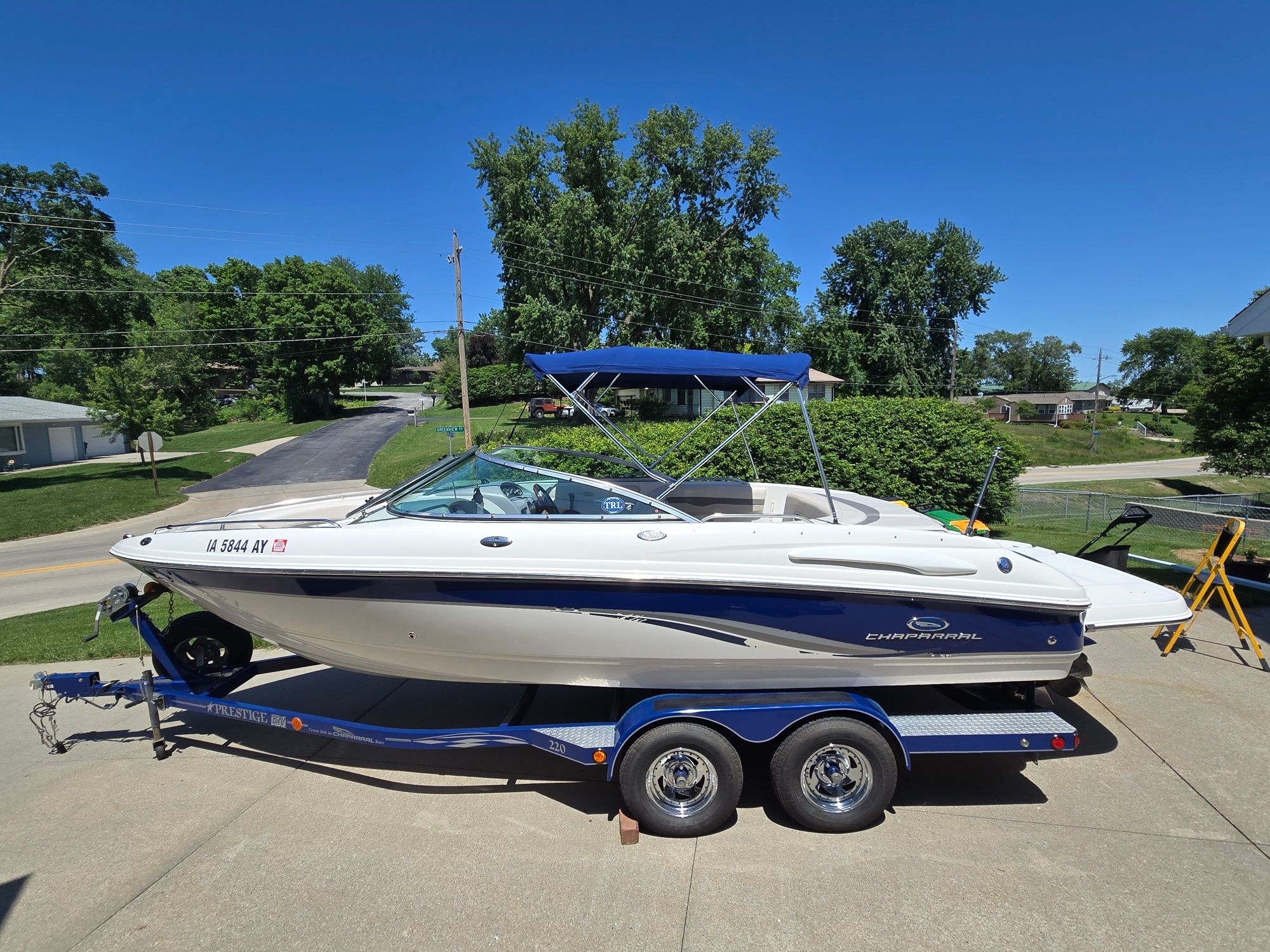 A 2005 Chaparral 220 SSi boat on a trailer in a driveway.