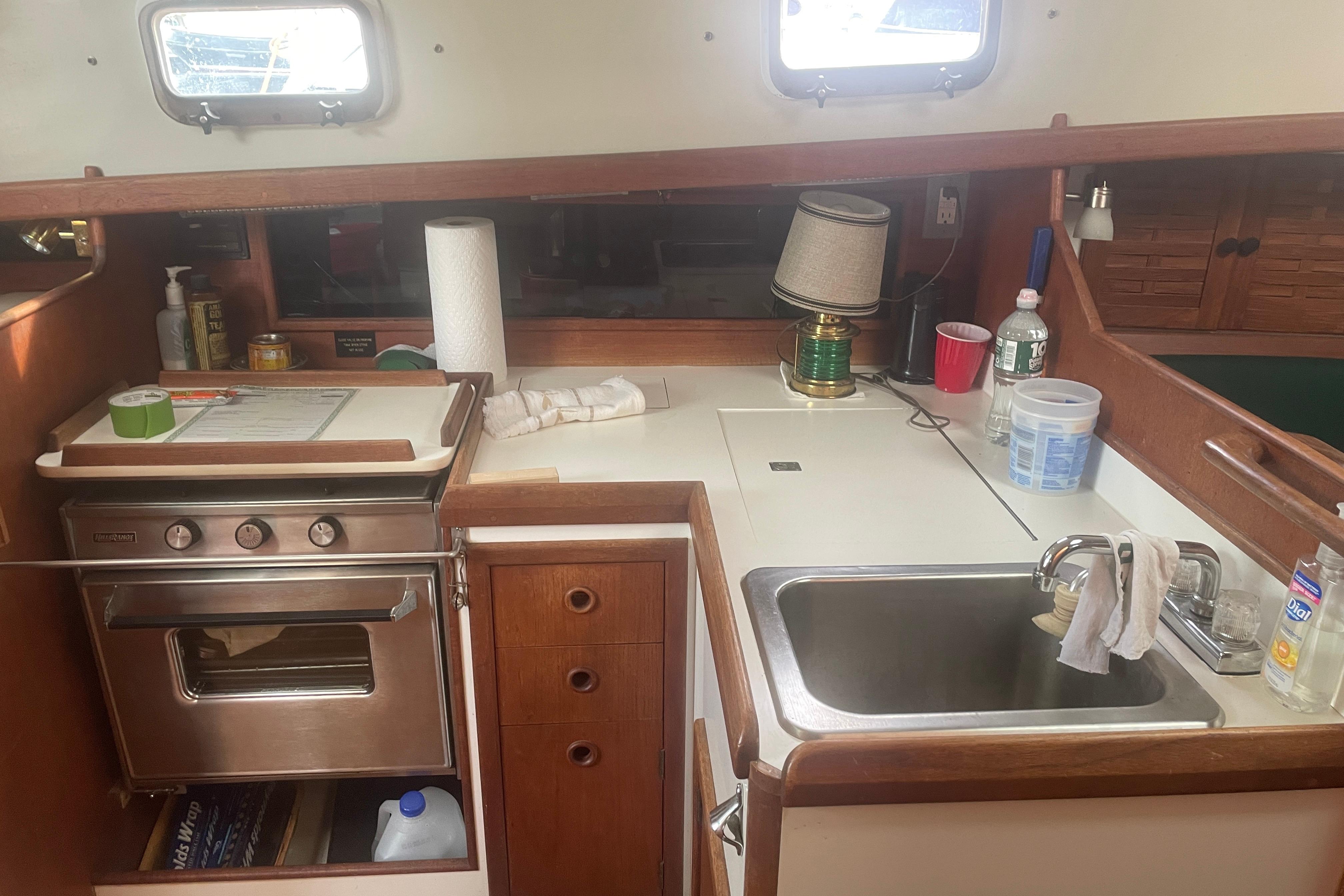 Compact kitchen area in a 1981 Nonsuch 30 Classic sailboat, featuring a stove and sink.
