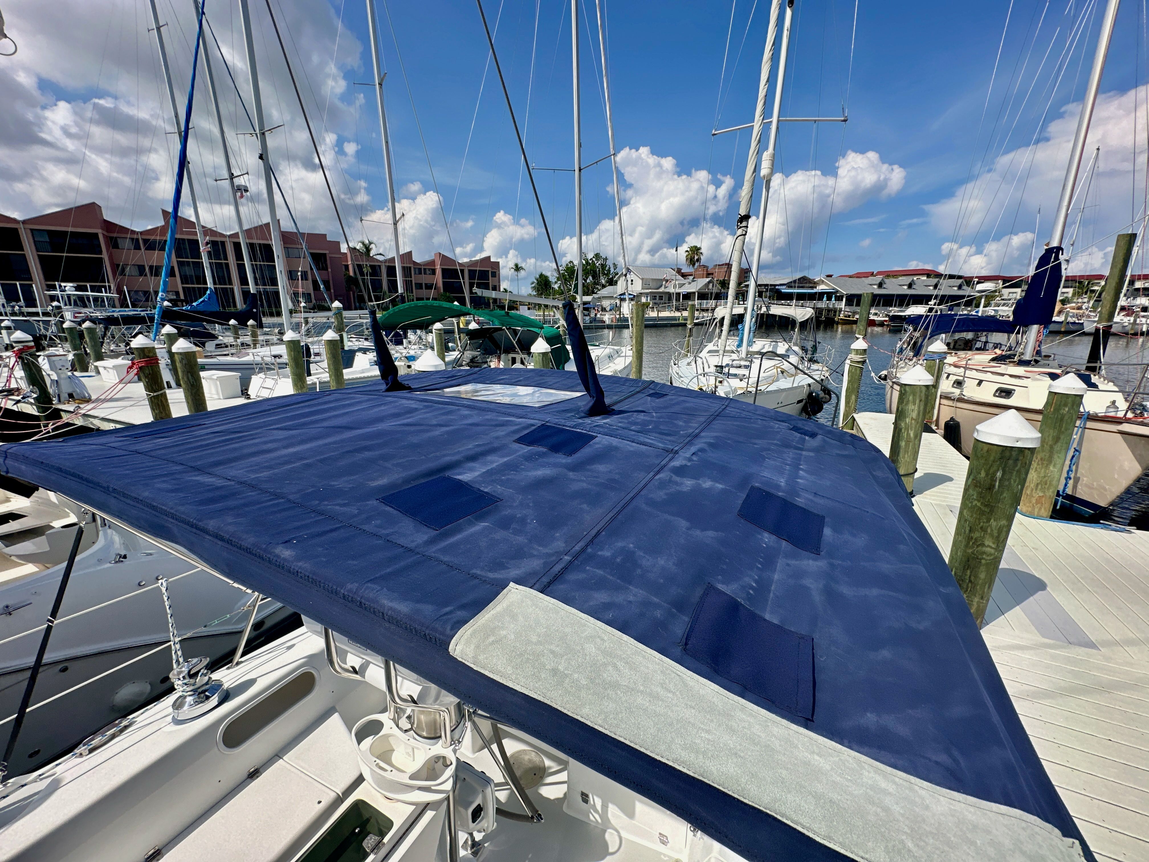 2005 Catalina 36 sailboat with blue cover docked at marina under clear sky.