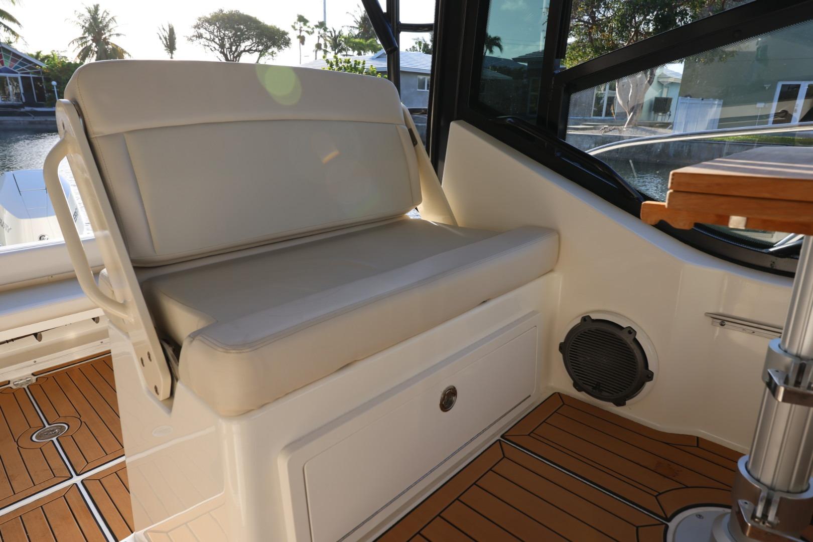 2025 Boston Whaler 325 Conquest interior seating with teak flooring and window view.