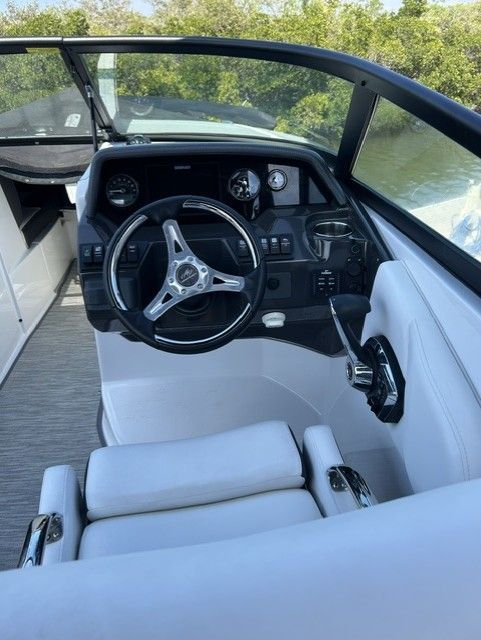 The cockpit of a modern boat with a white seat and black steering wheel.