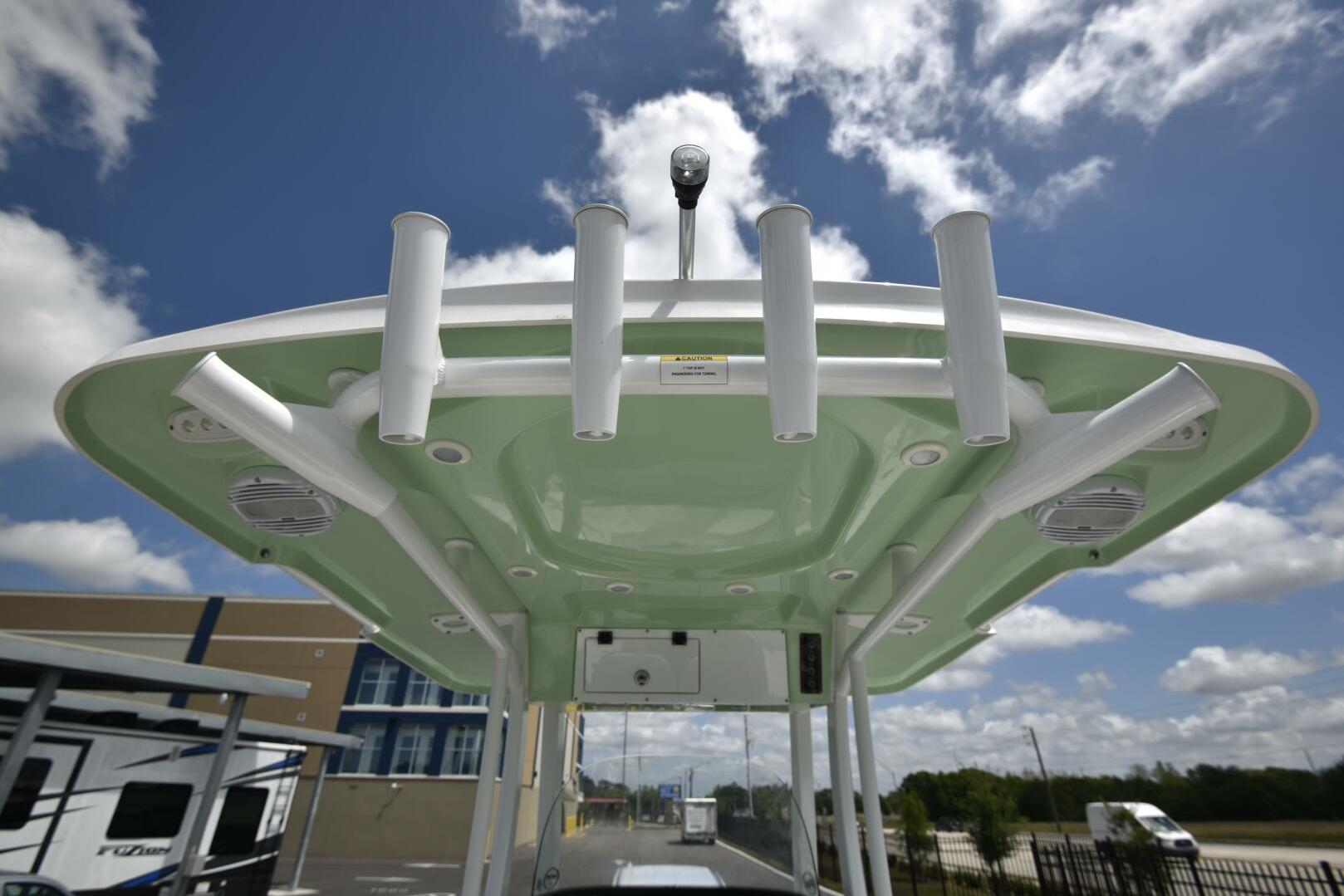2023 Sea Pro 239 Deep V CC boat with rod holders and speakers under a clear sky.