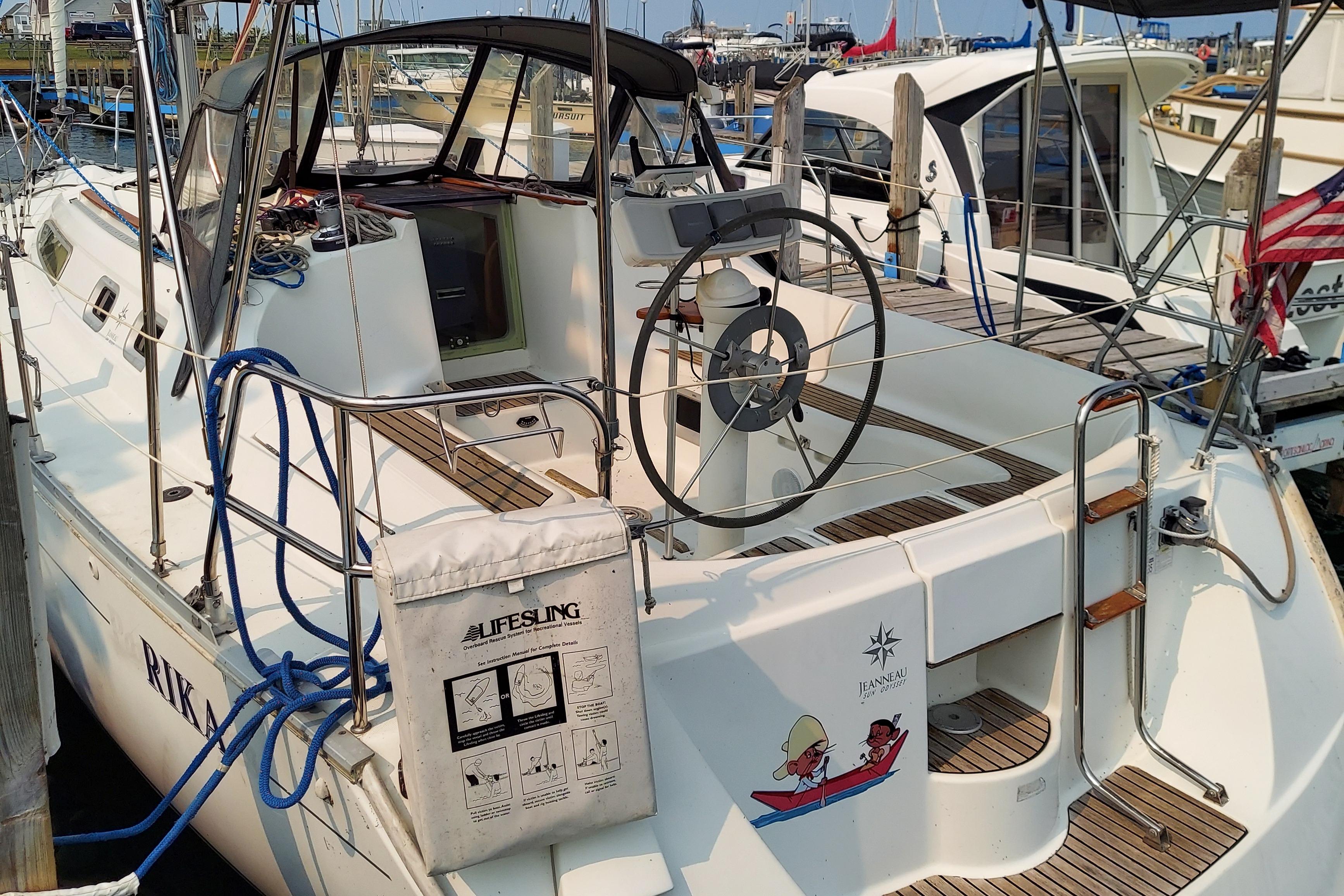 Jeanneau 34.2 sailboat, 2000 model, docked at marina with visible steering wheel and lifesling.