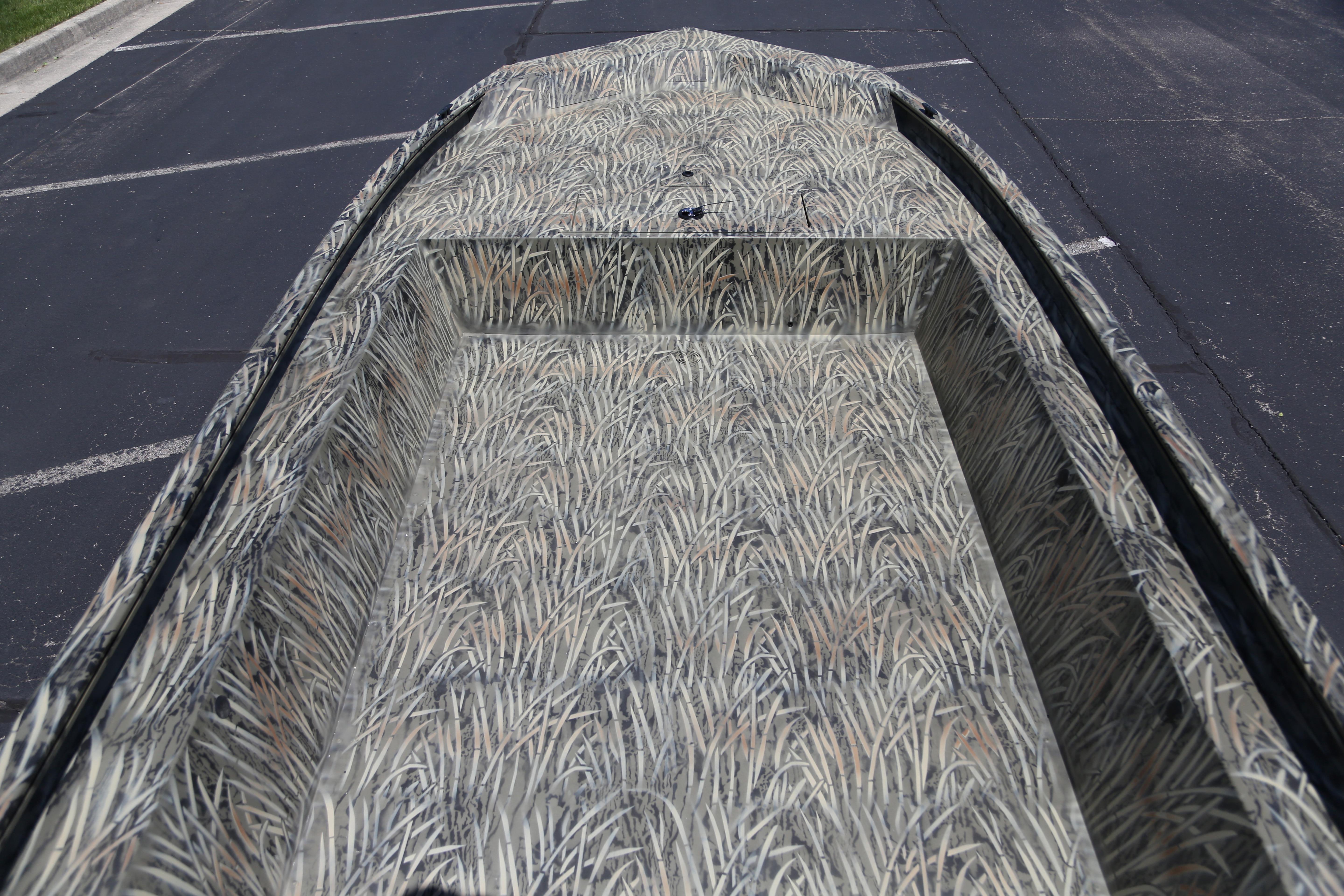 2026 Tracker Grizzly 1754 Utility boat with camouflage pattern in a parking lot.