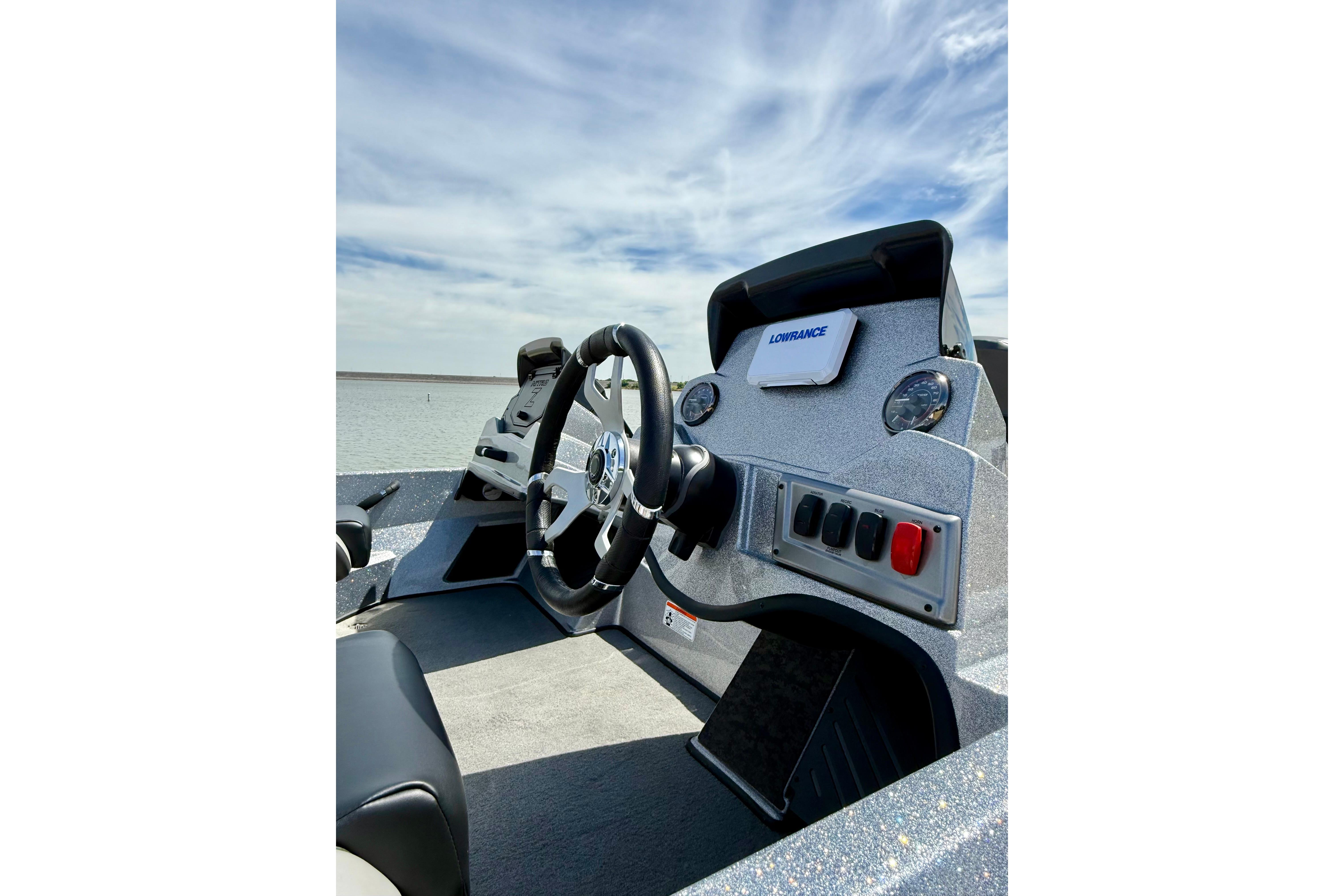 2026 Nitro Z19 XL boat dashboard with steering wheel and control panel under a blue sky.