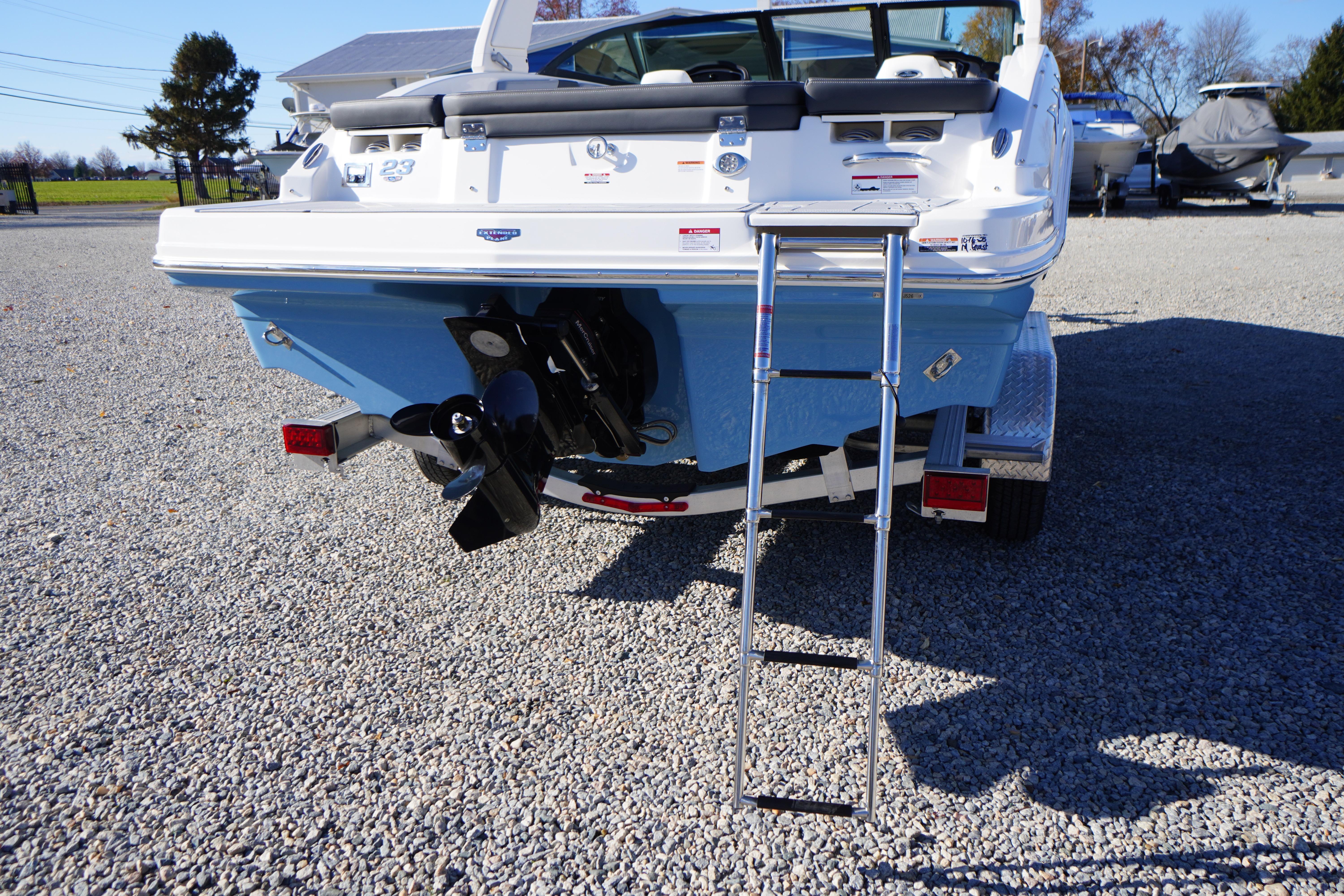 2026 Chaparral 23 SSi boat rear view with ladder on gravel surface.