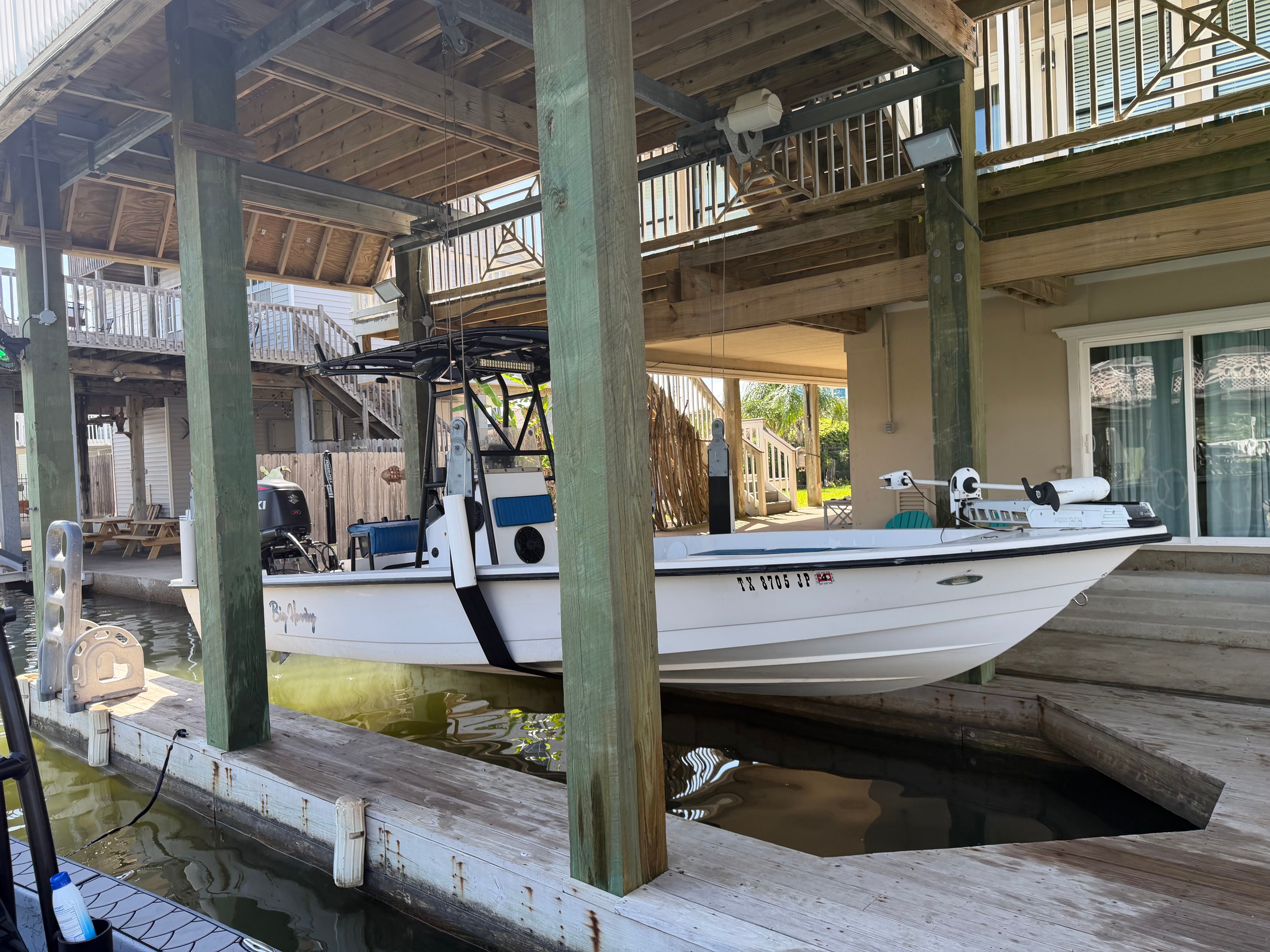 A white boat is docked under a covered pier.