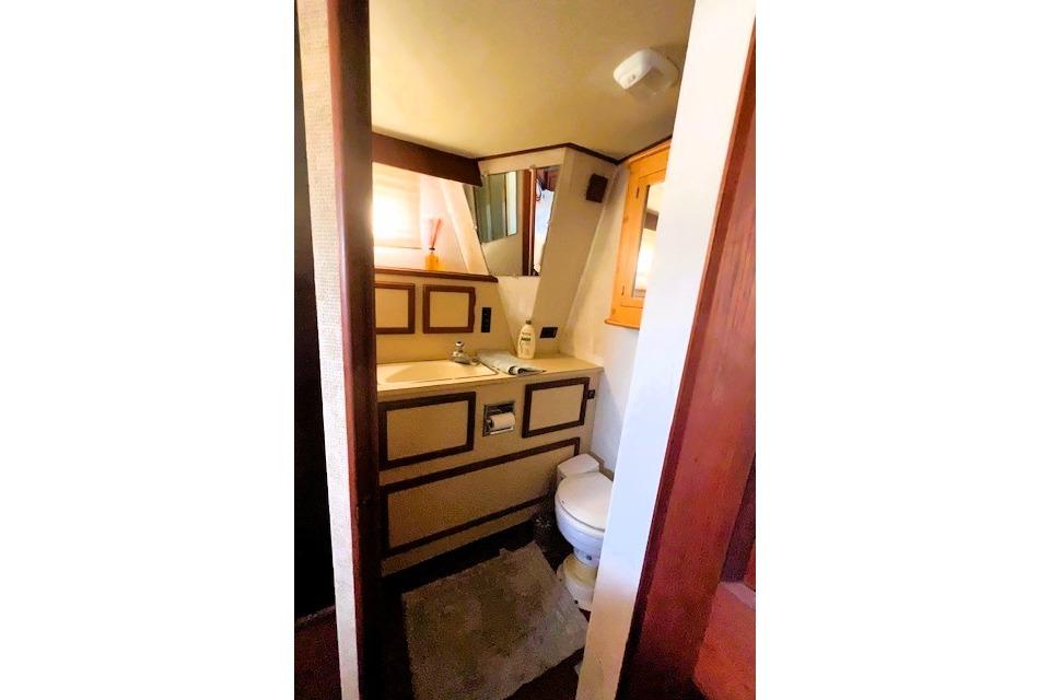 Small bathroom interior of 1980 Viking 43 Convertible yacht, featuring sink and toilet.