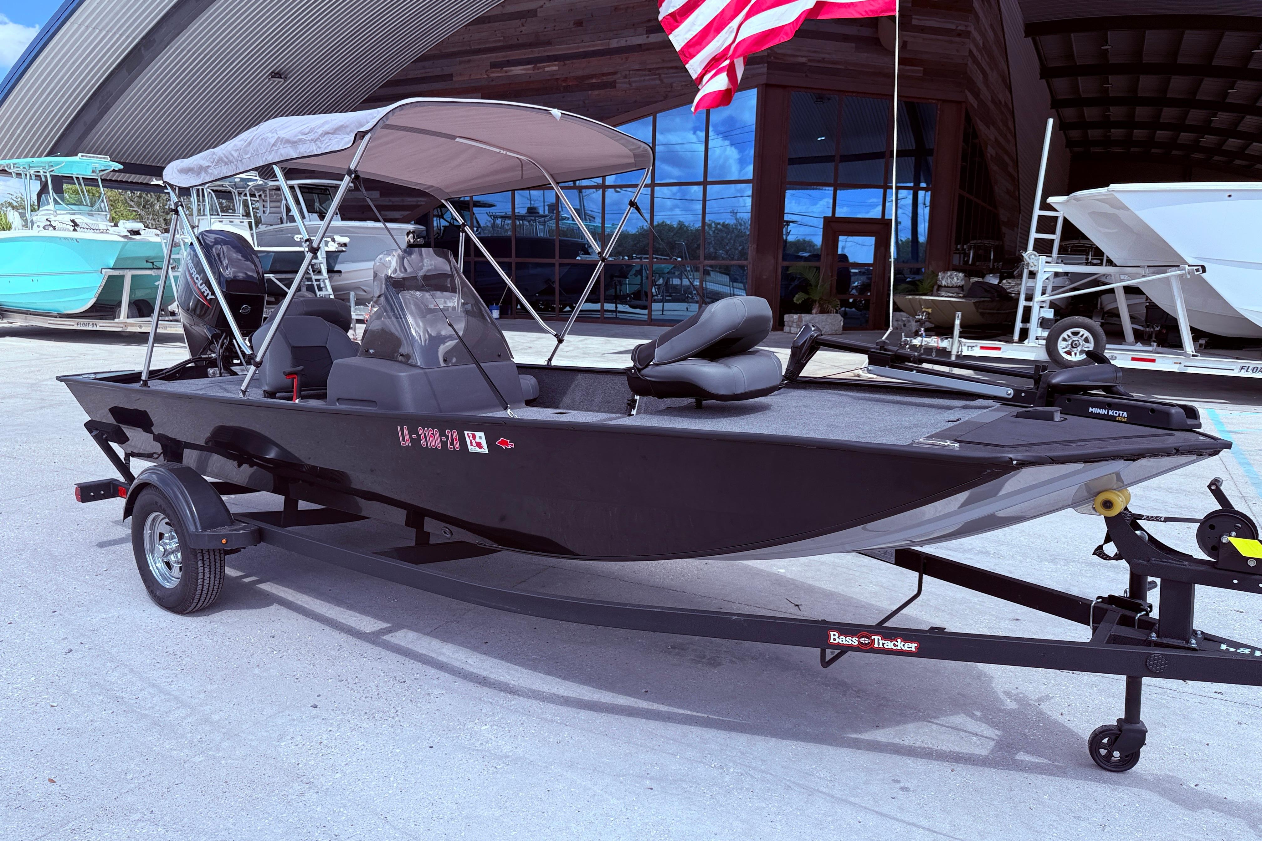 2025 Bass Tracker Classic XL boat with canopy and trailer, parked outdoors.