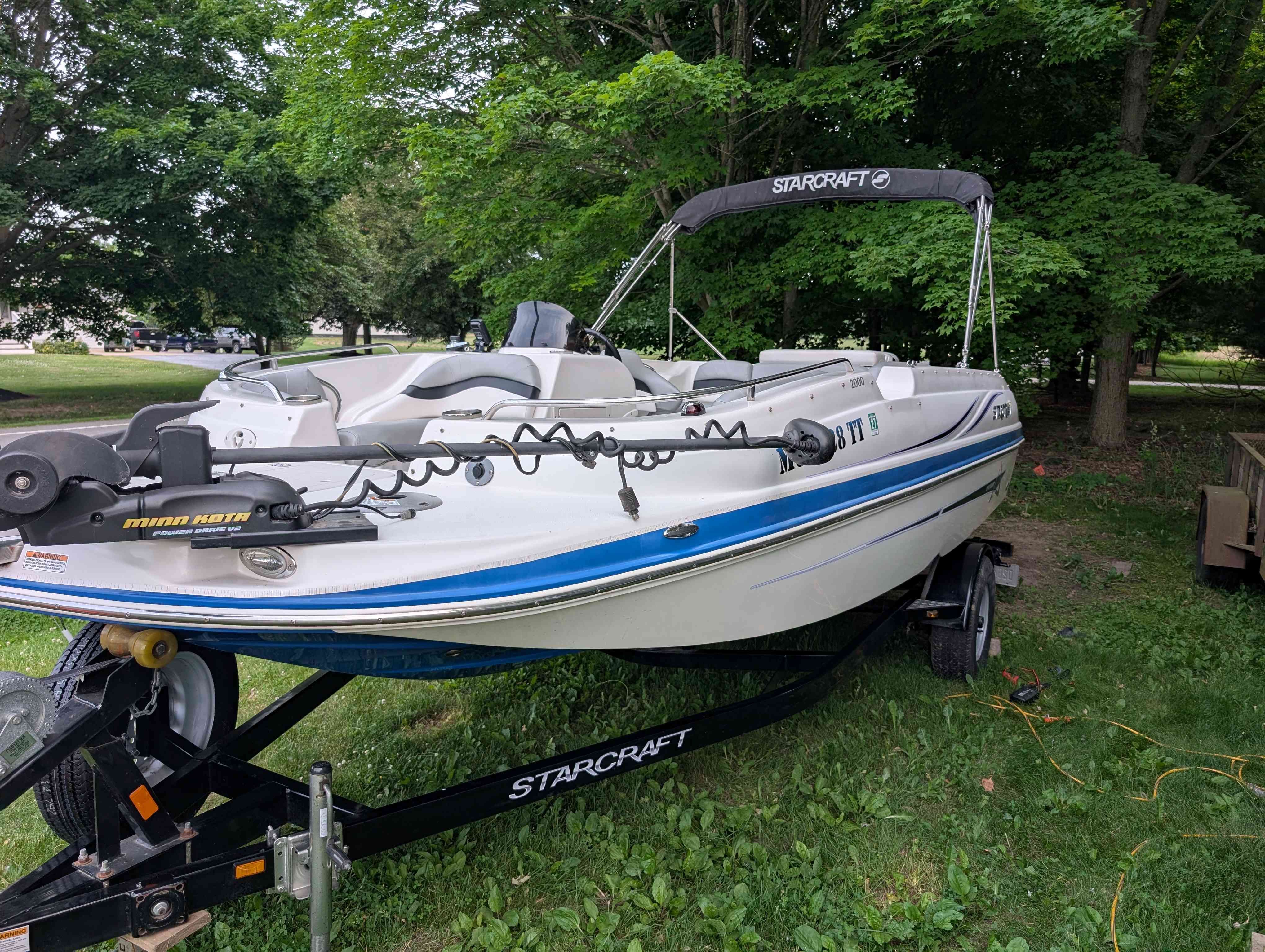 2015 Starcraft 2000 boat on trailer in a lush green setting.