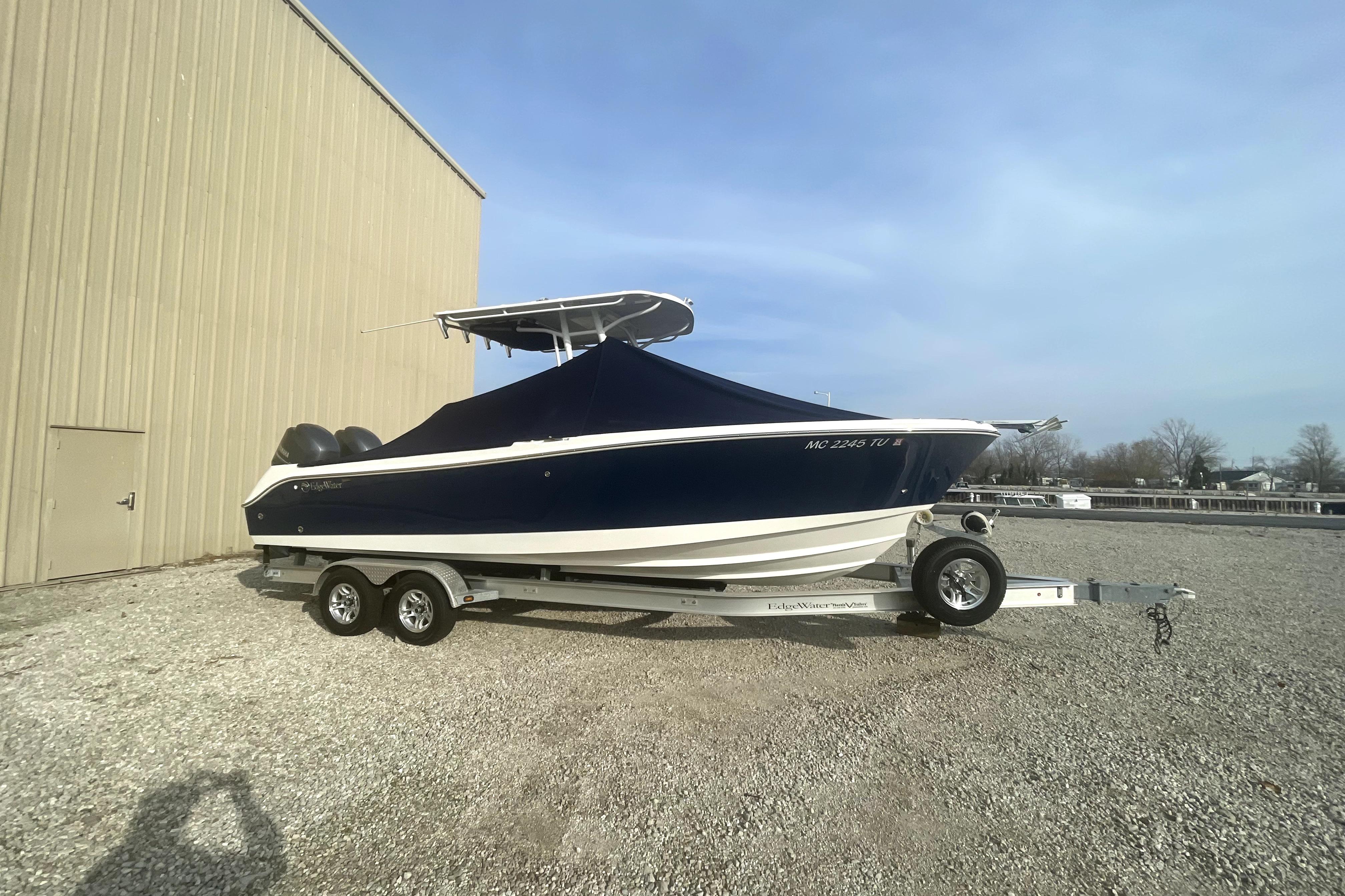 2015 Edgewater 245CC boat on trailer, covered, parked beside a building.
