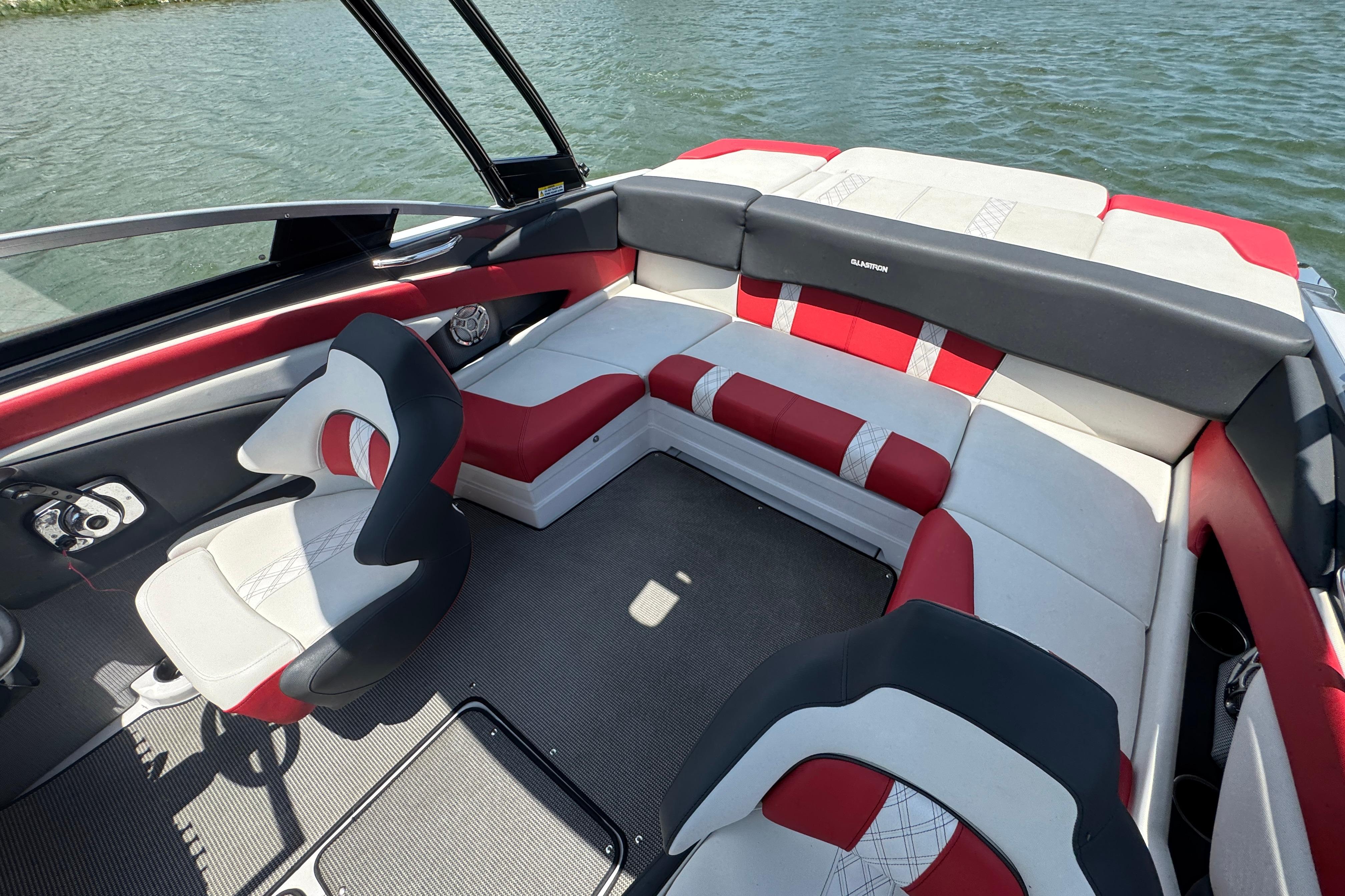 2017 Glastron GT 225 boat interior with red and white seating, on a calm lake.