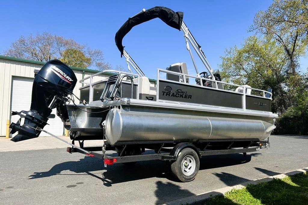 2026 Sun Tracker Bass Buggy 18 DLX pontoon boat on trailer, parked outdoors.