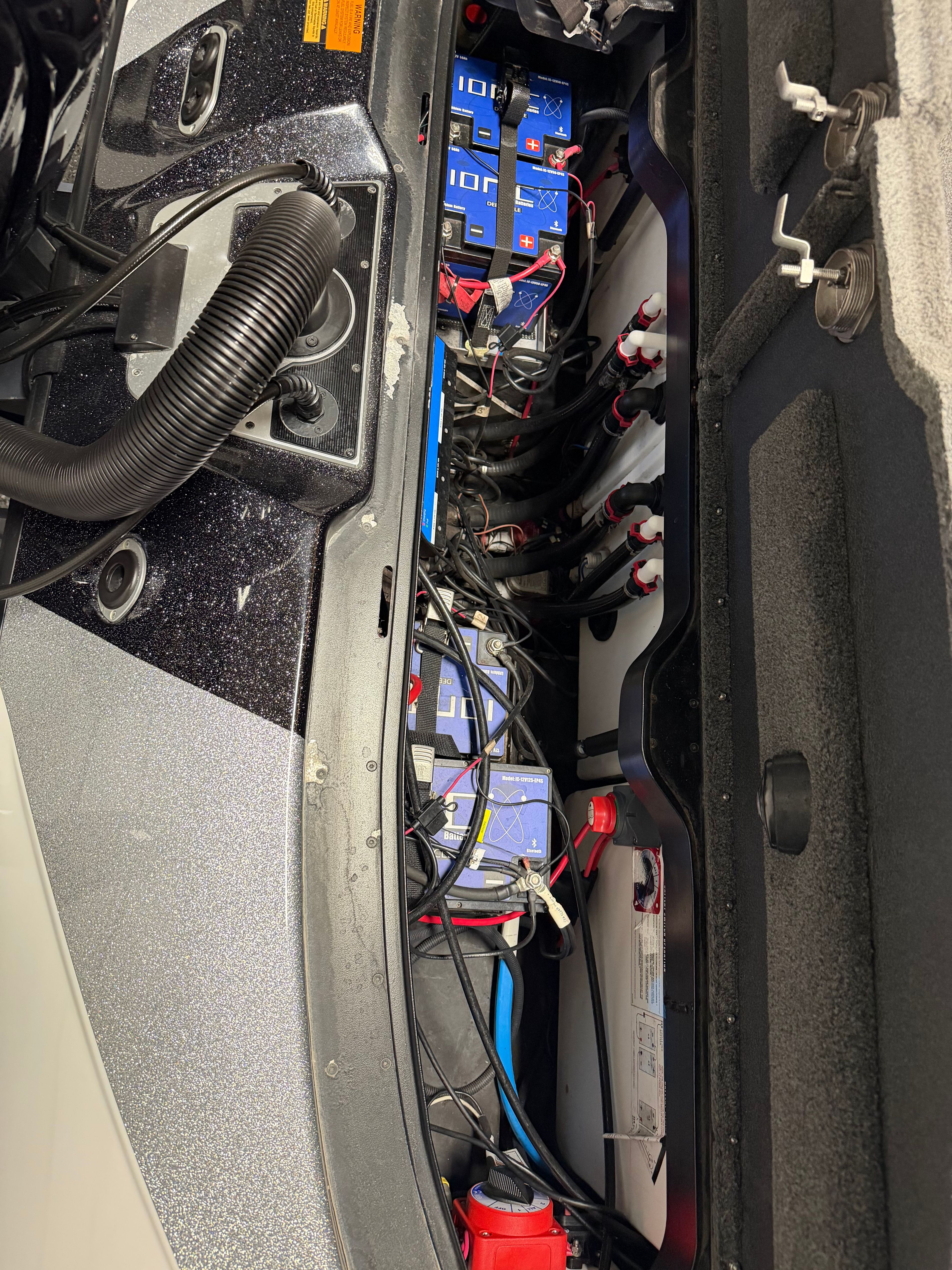 View of a boat's engine compartment with multiple batteries and cables.