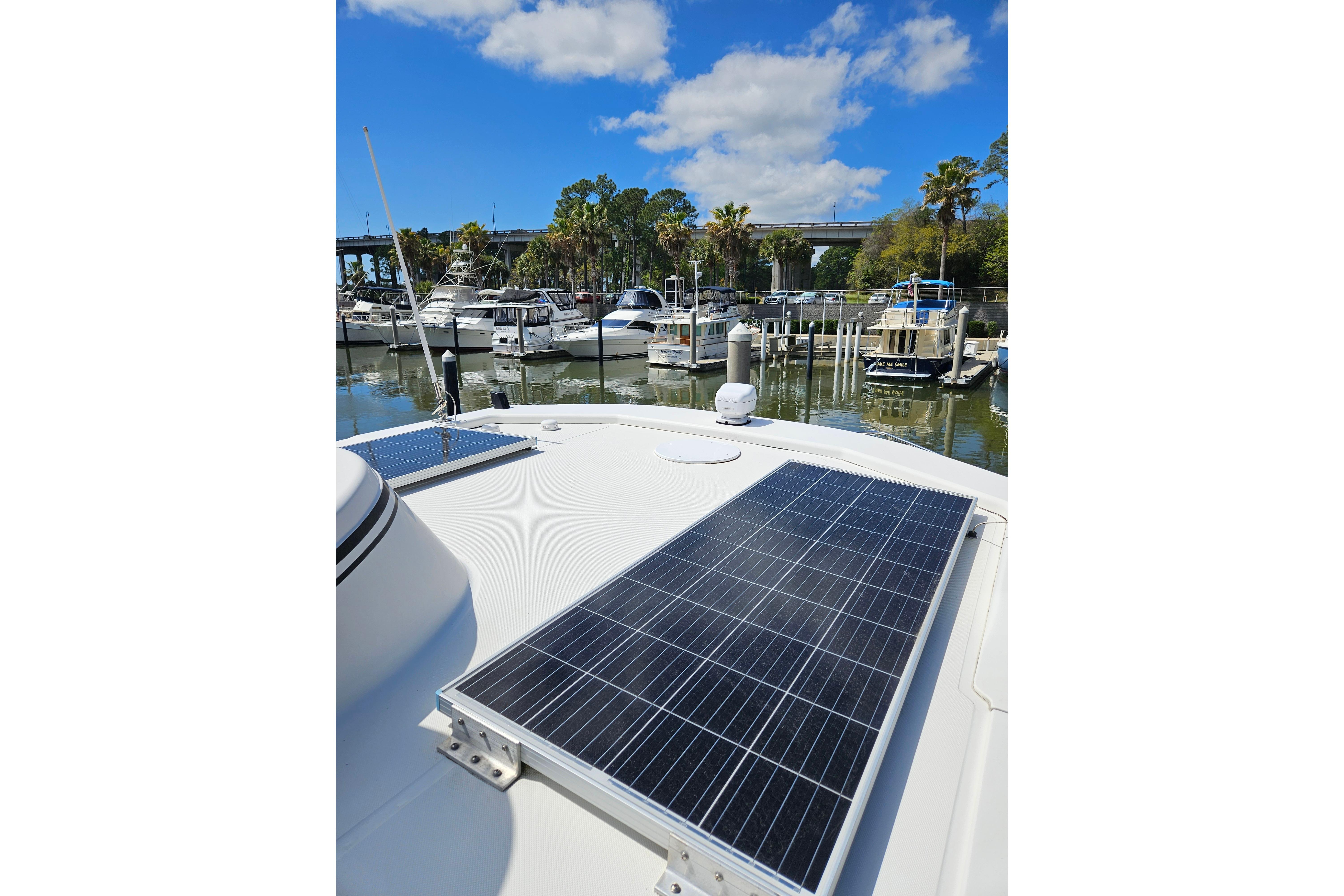 2006 American Tug AT with solar panels docked at a marina under a blue sky.