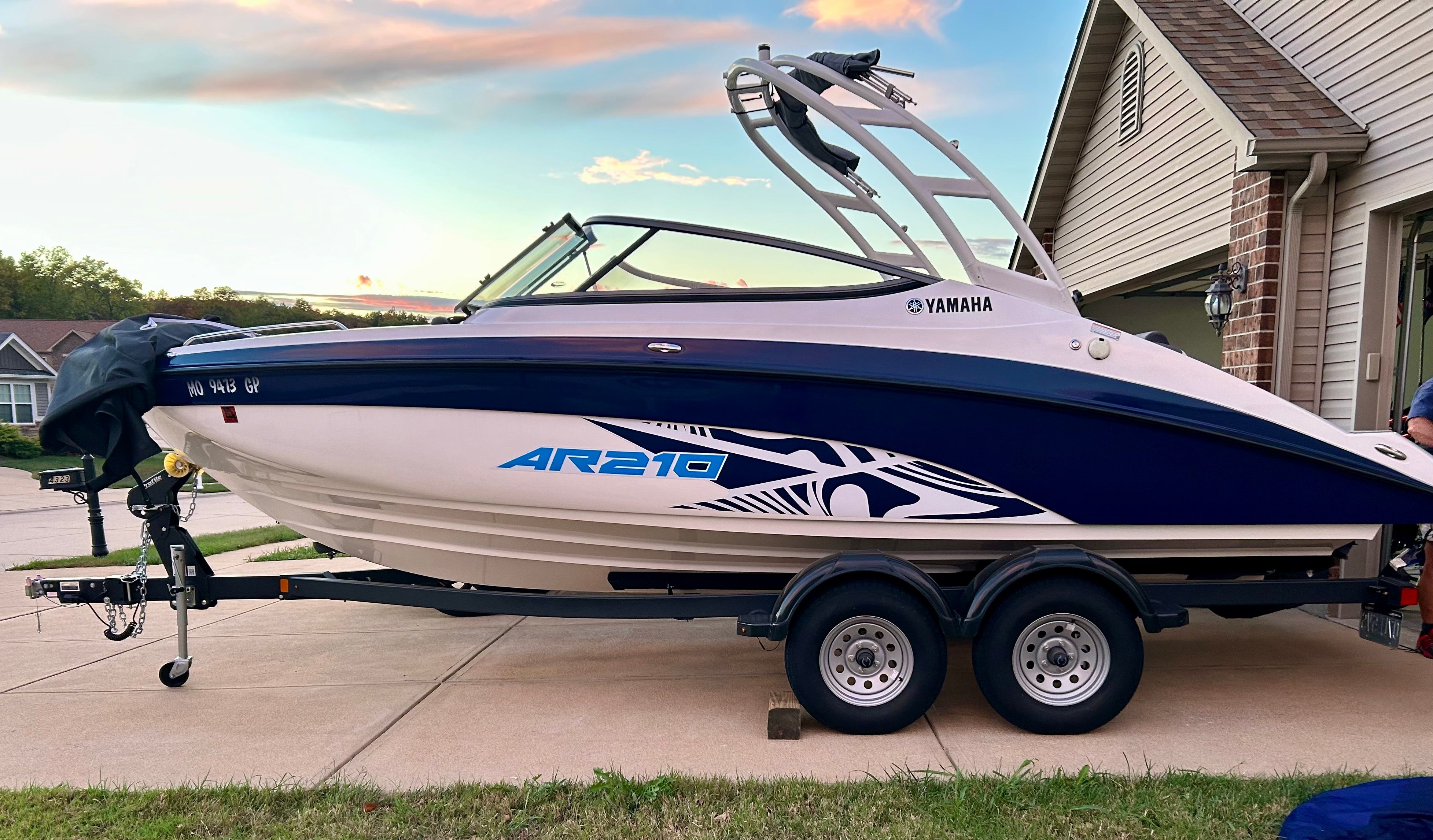 A Yamaha AR210 boat is on a trailer in a driveway.