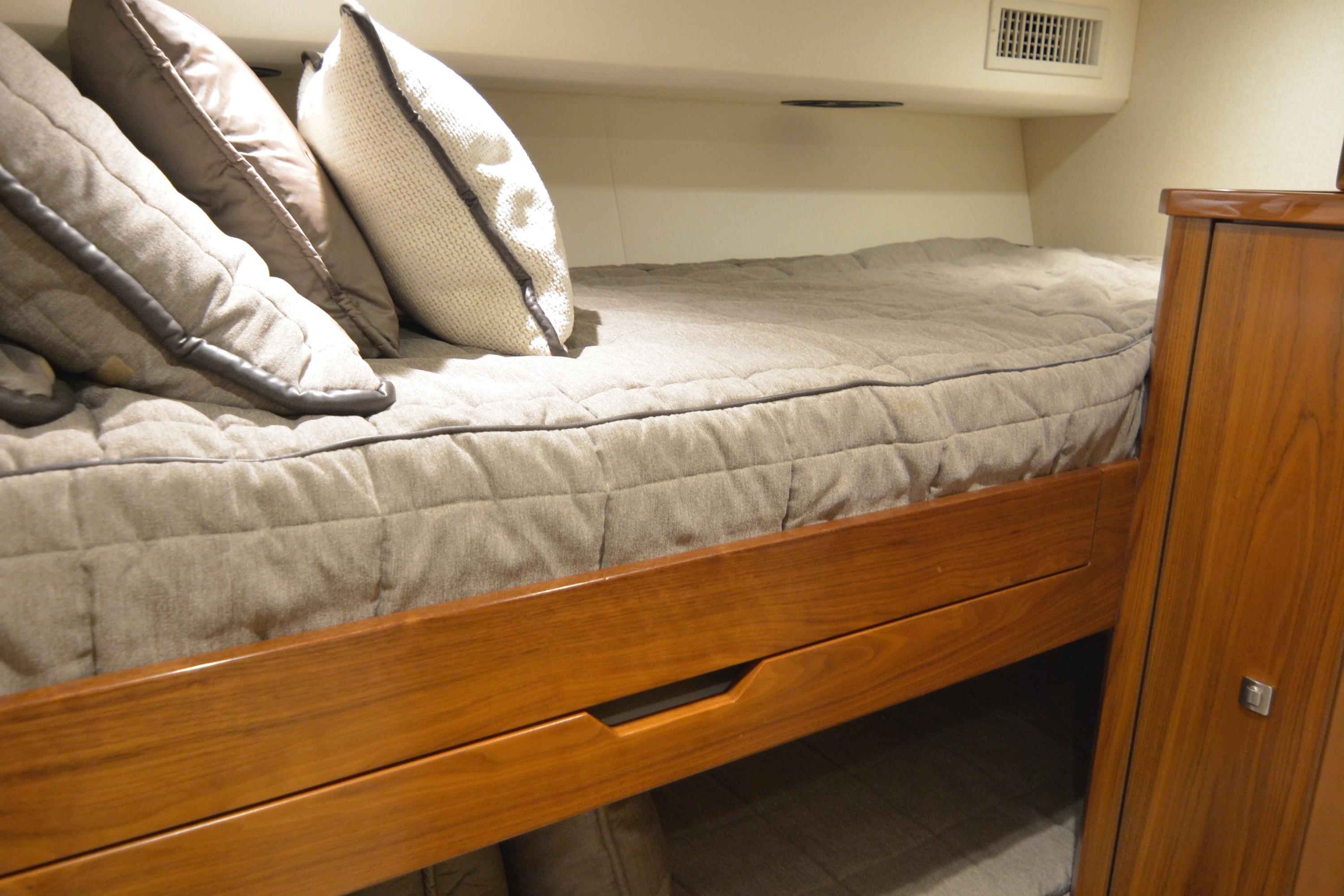 Cozy cabin bed in 2019 Viking 68 Convertible yacht with wooden accents and plush pillows.