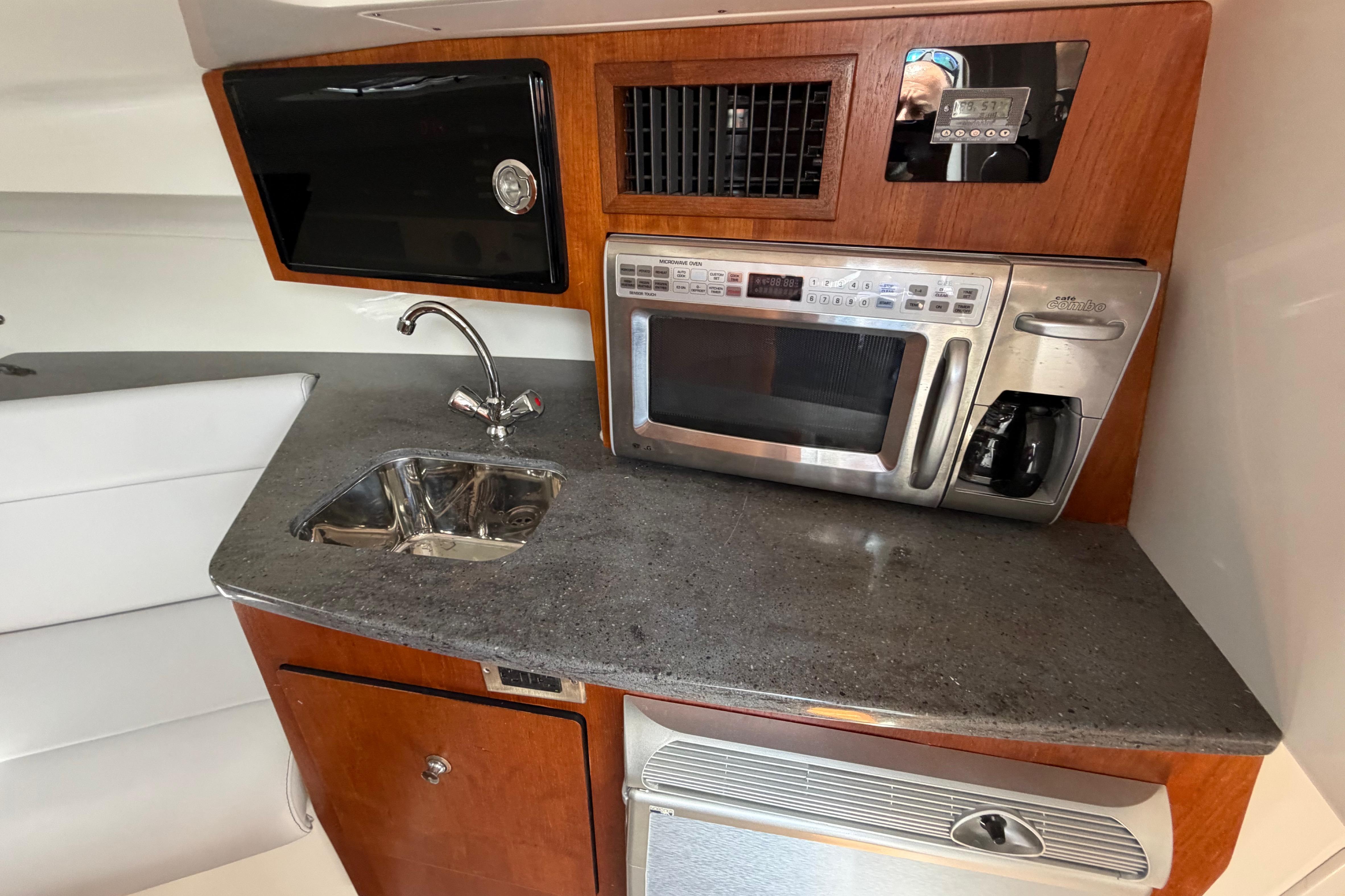 Compact kitchen area in a 2009 Everglades 350LX boat with sink and microwave.