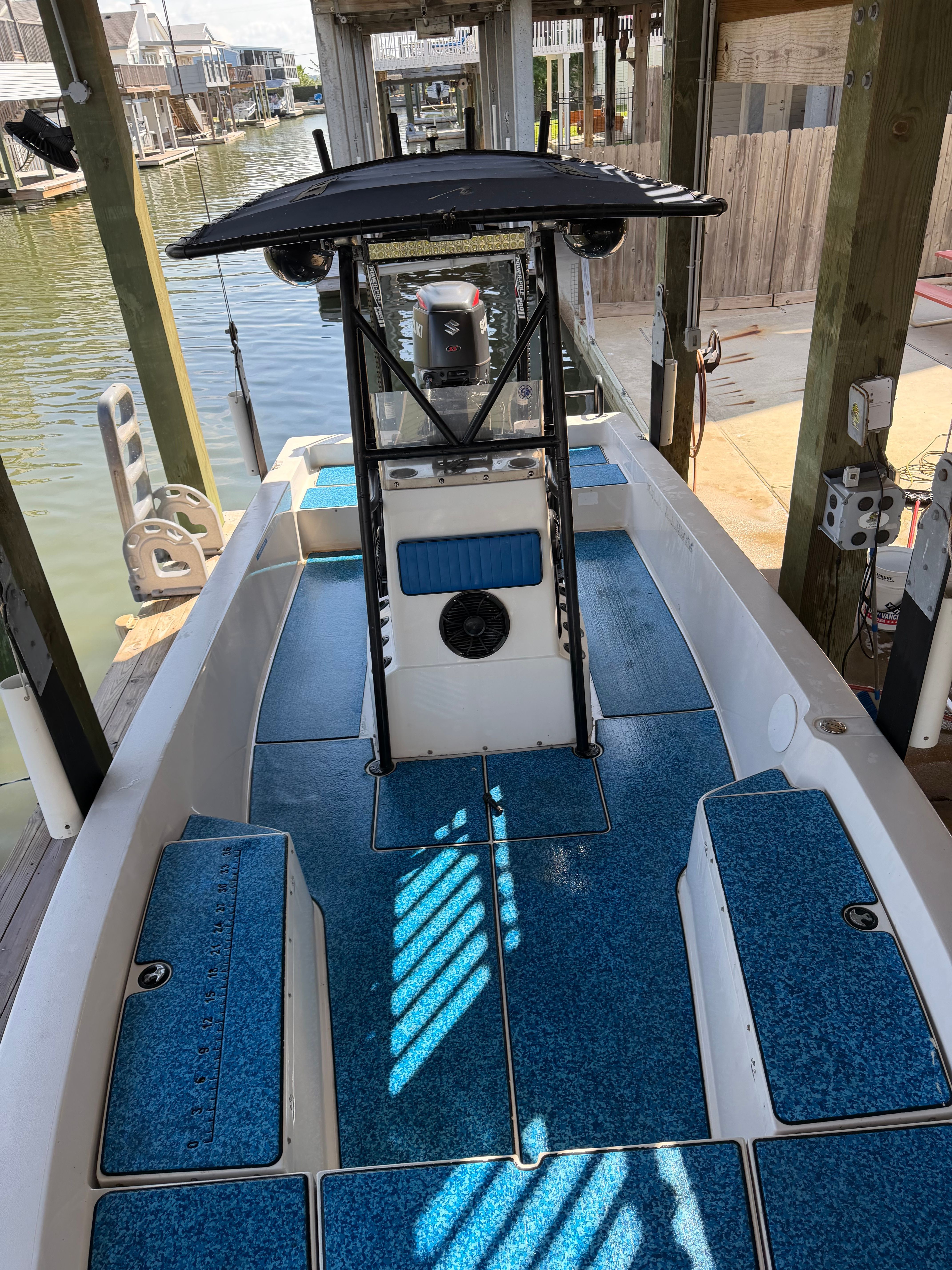 A blue and white bay boat is docked under a covered area.