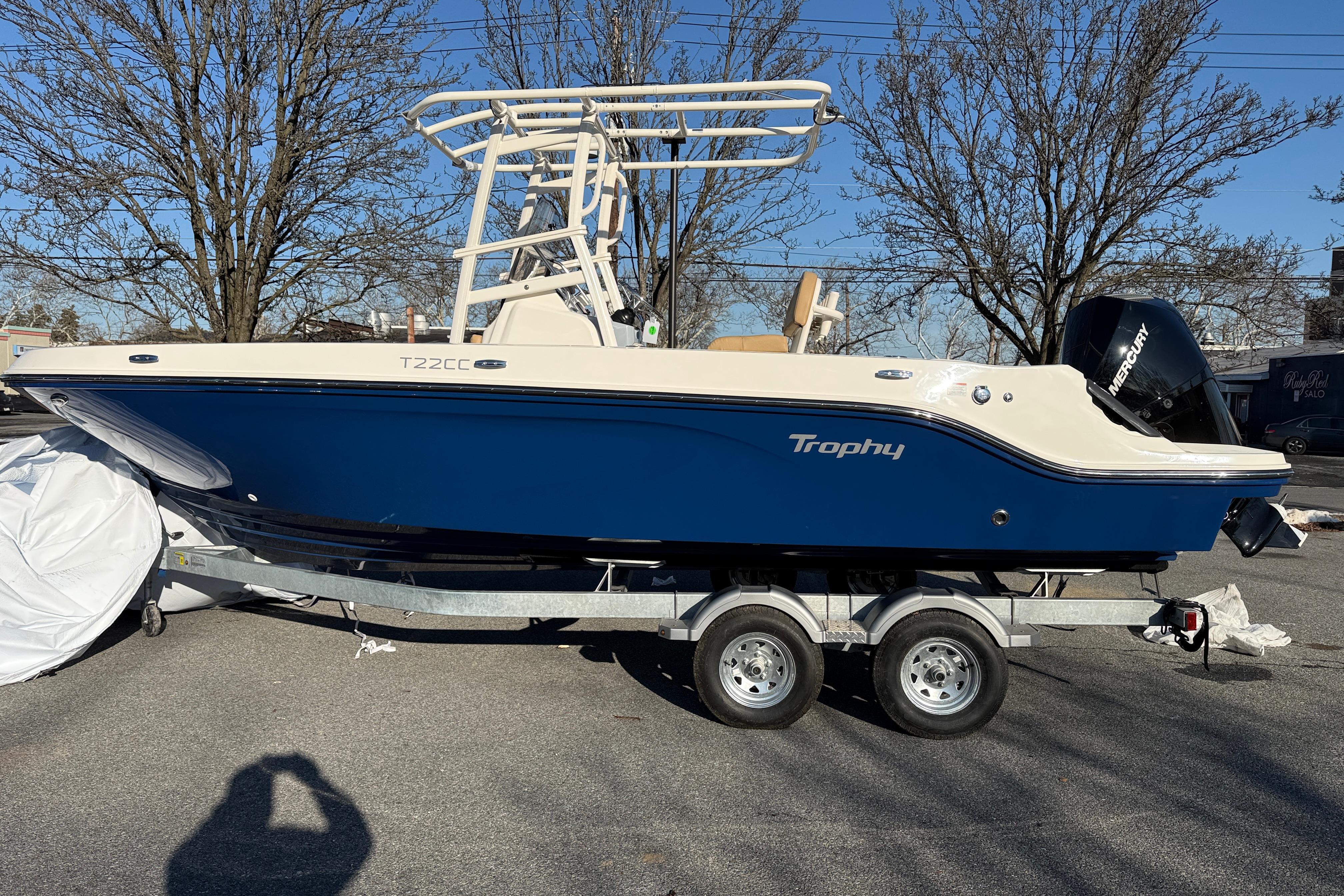 2026 Bayliner Trophy T22CC boat on trailer, blue hull, parked outdoors.