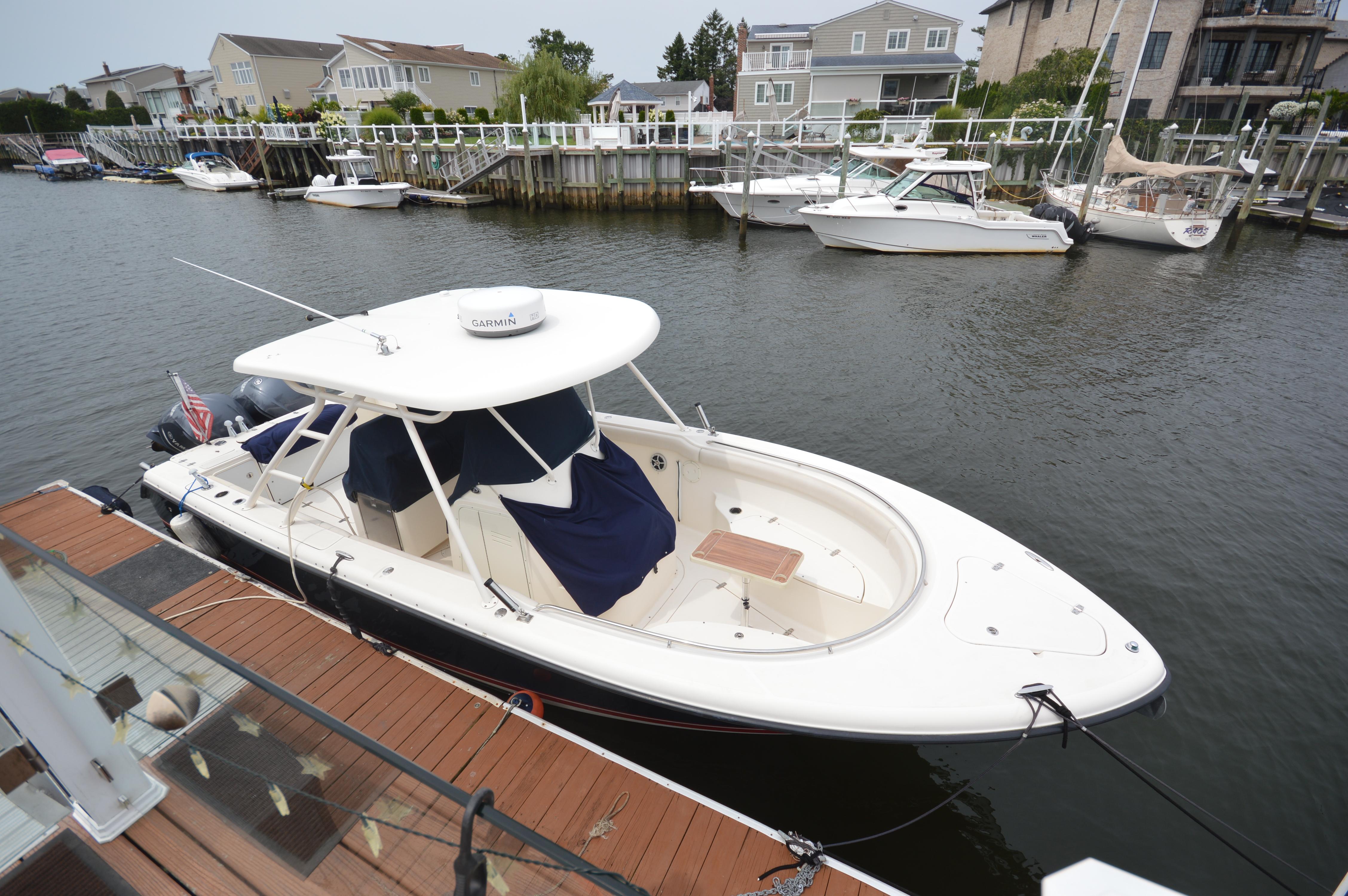 2012 Pursuit 280 boat docked in a marina with waterfront homes.