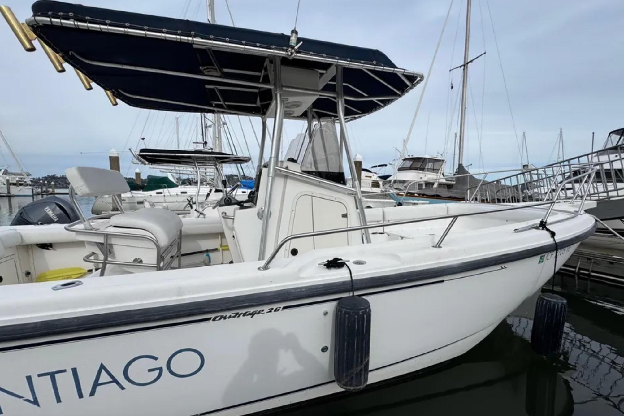 2001 Boston Whaler 26 Outrage boat docked at marina, featuring sleek design and canopy.