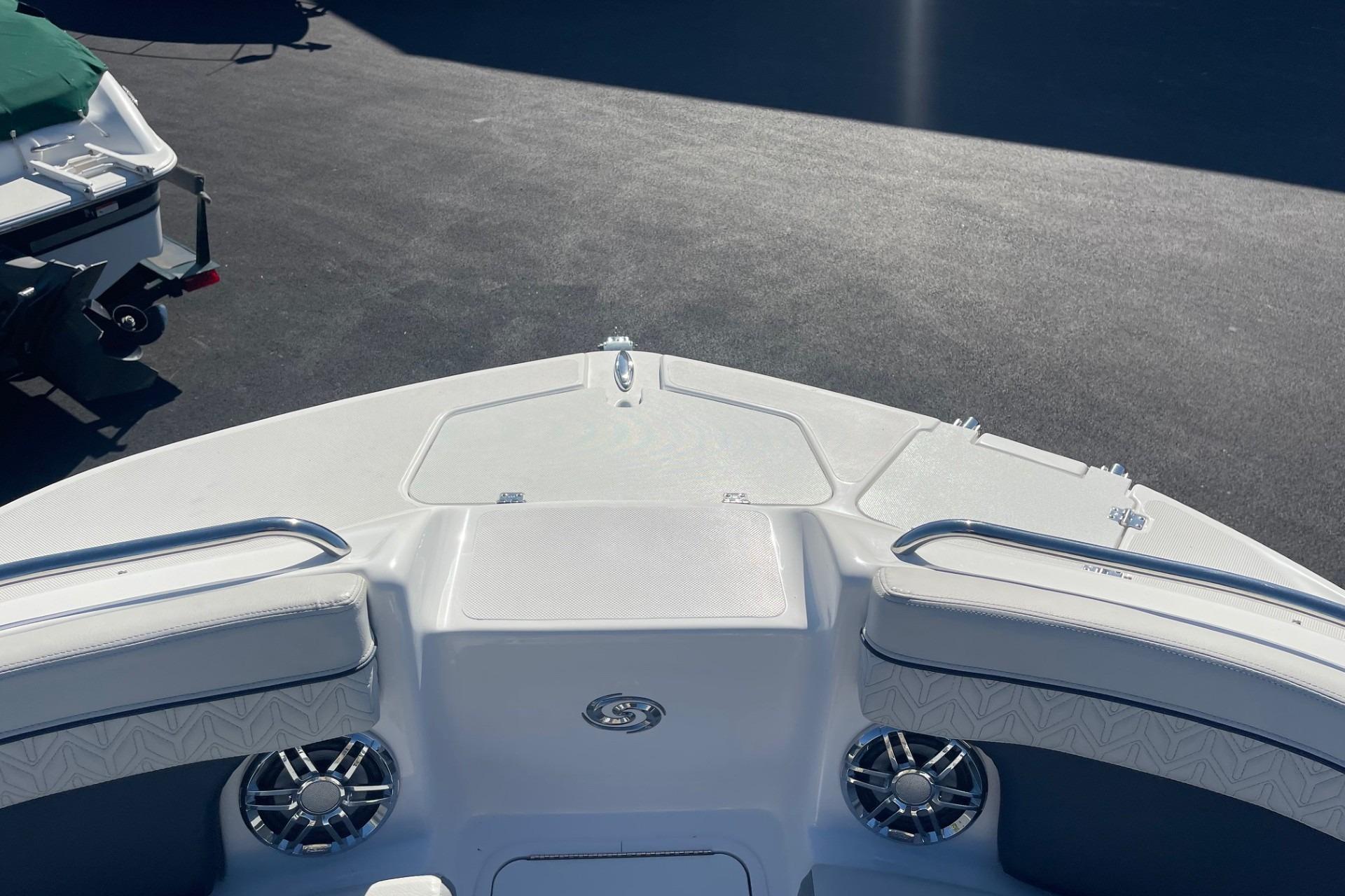 2023 Hurricane SunDeck 2400 OB boat deck with seating and speakers in sunlight.