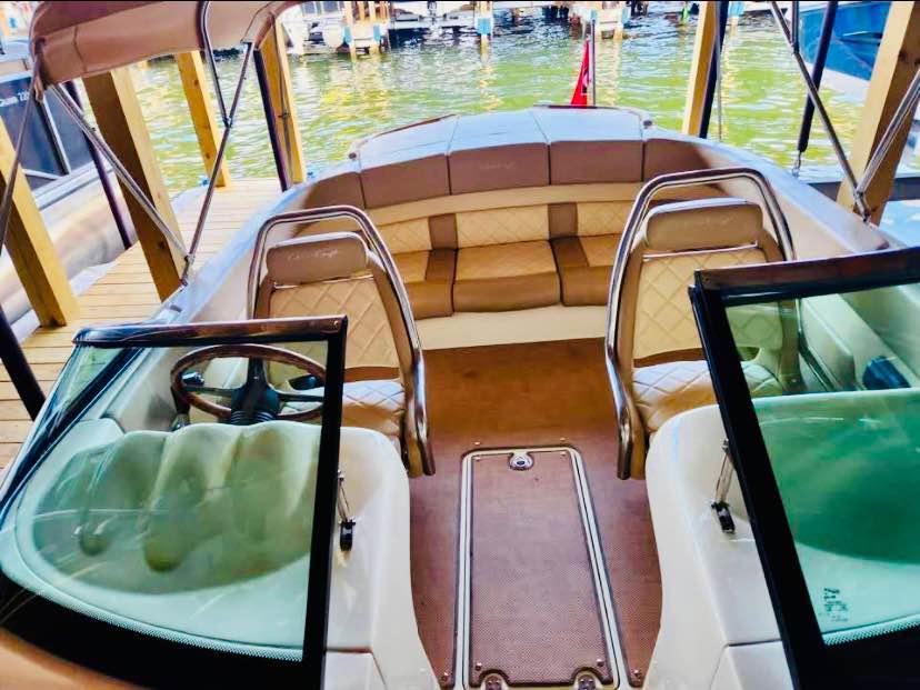 2016 Chris-Craft Carina 21 boat interior with tan seating and steering wheel, docked by water.
