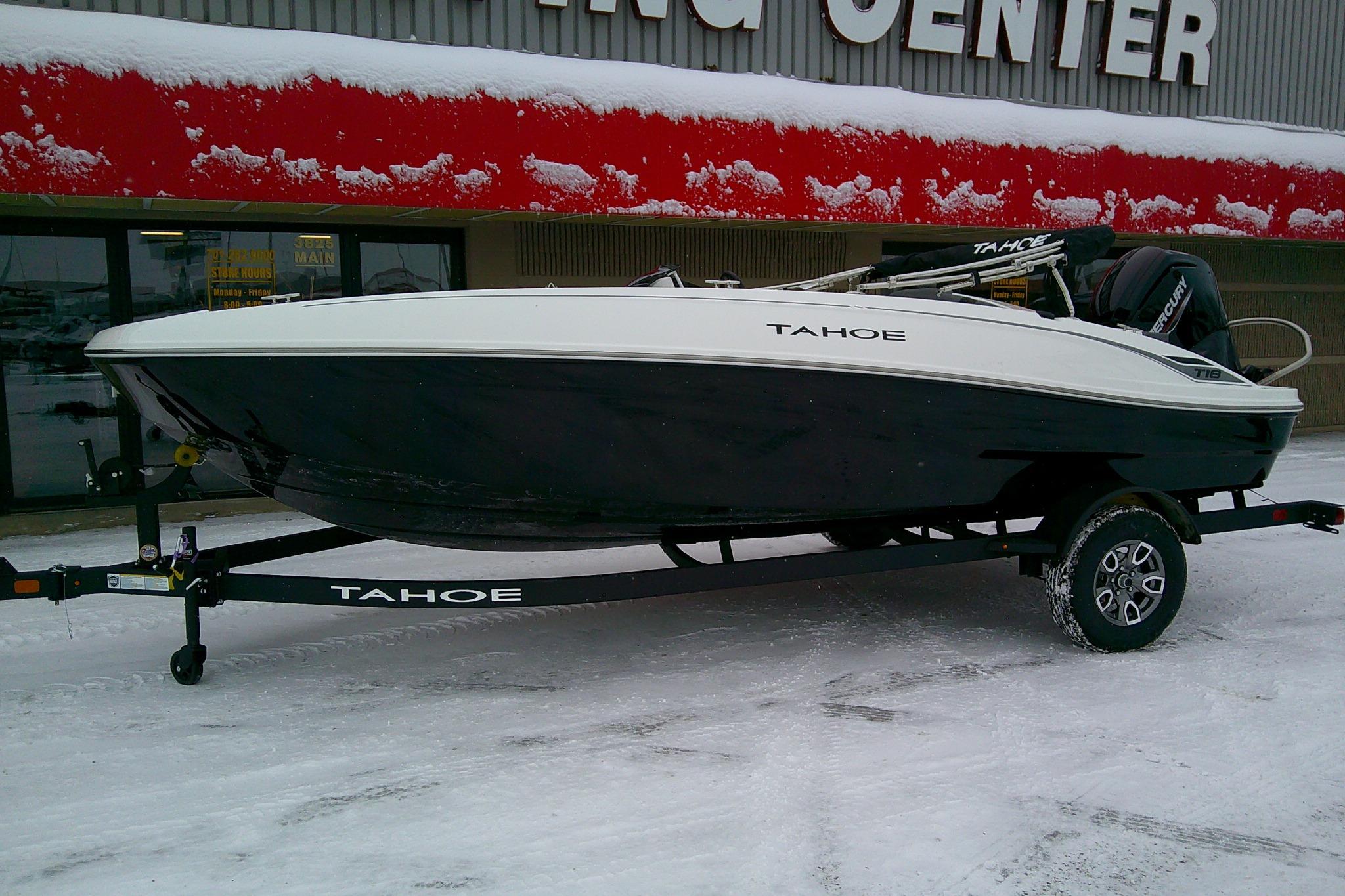 2026 Tahoe T18 boat on trailer in snowy setting outside dealership.