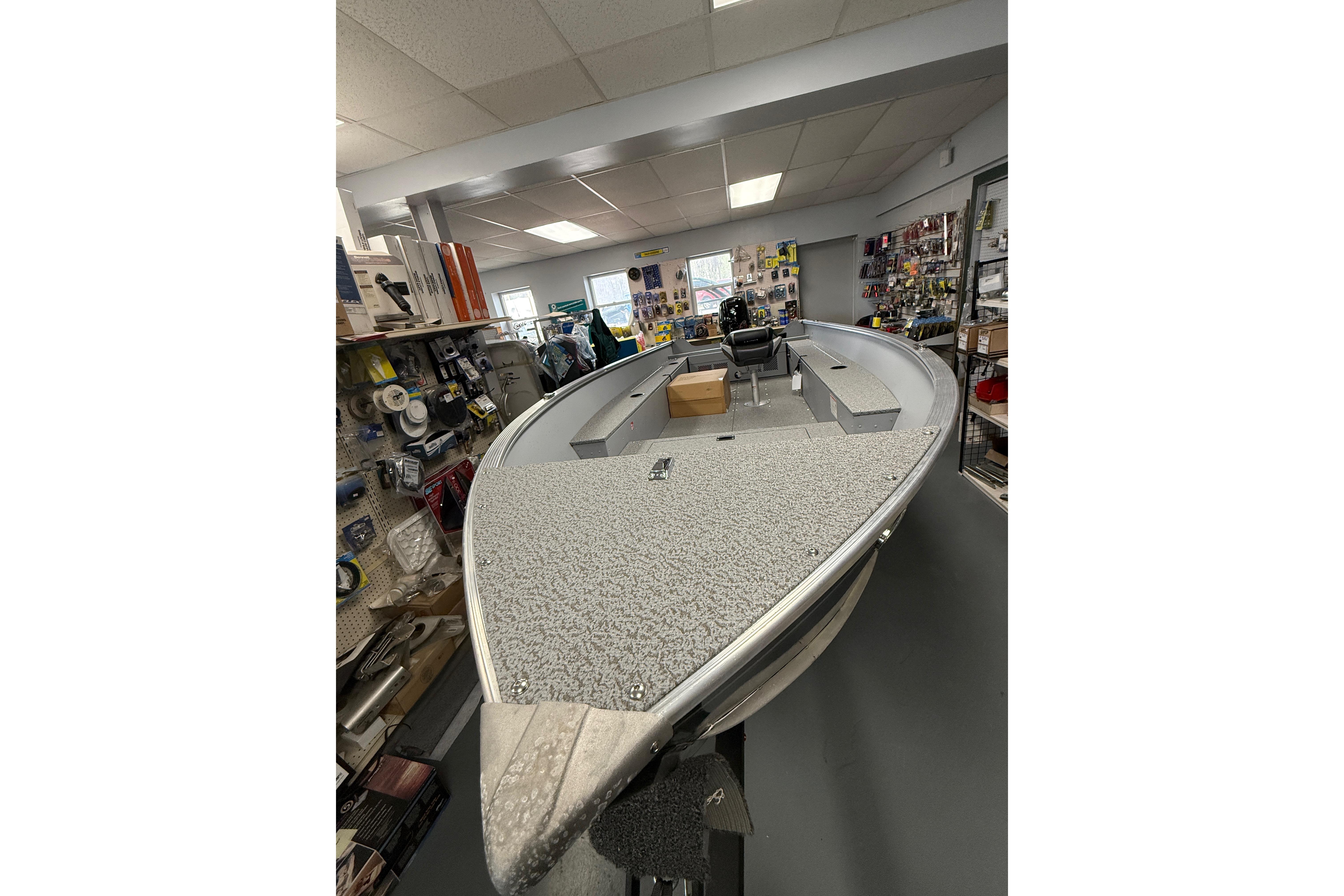 2026 Lund Fury 1600 Tiller boat displayed in a showroom with various accessories.