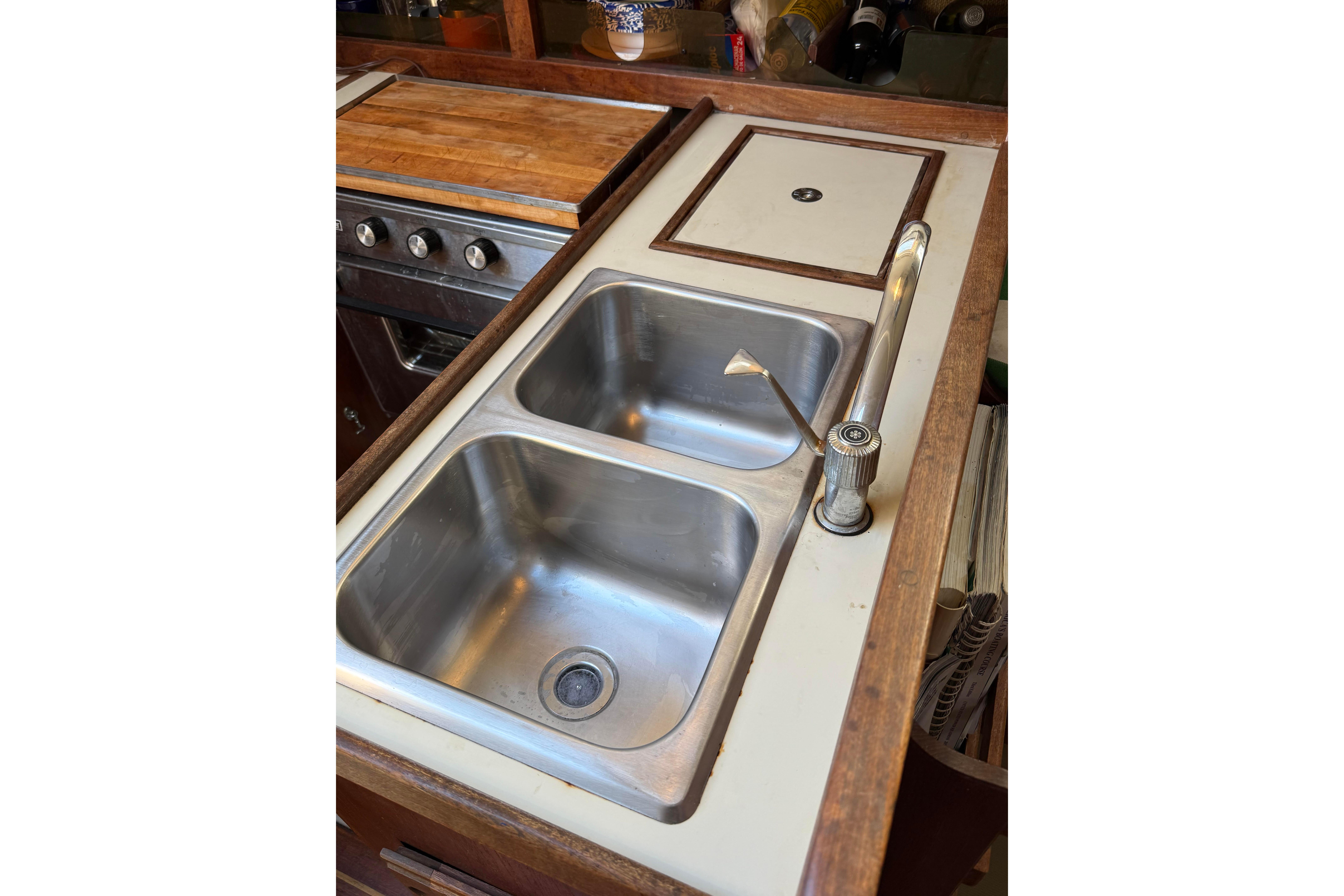 1983 O'Day 34 yacht kitchen with dual stainless steel sinks and wooden countertop.