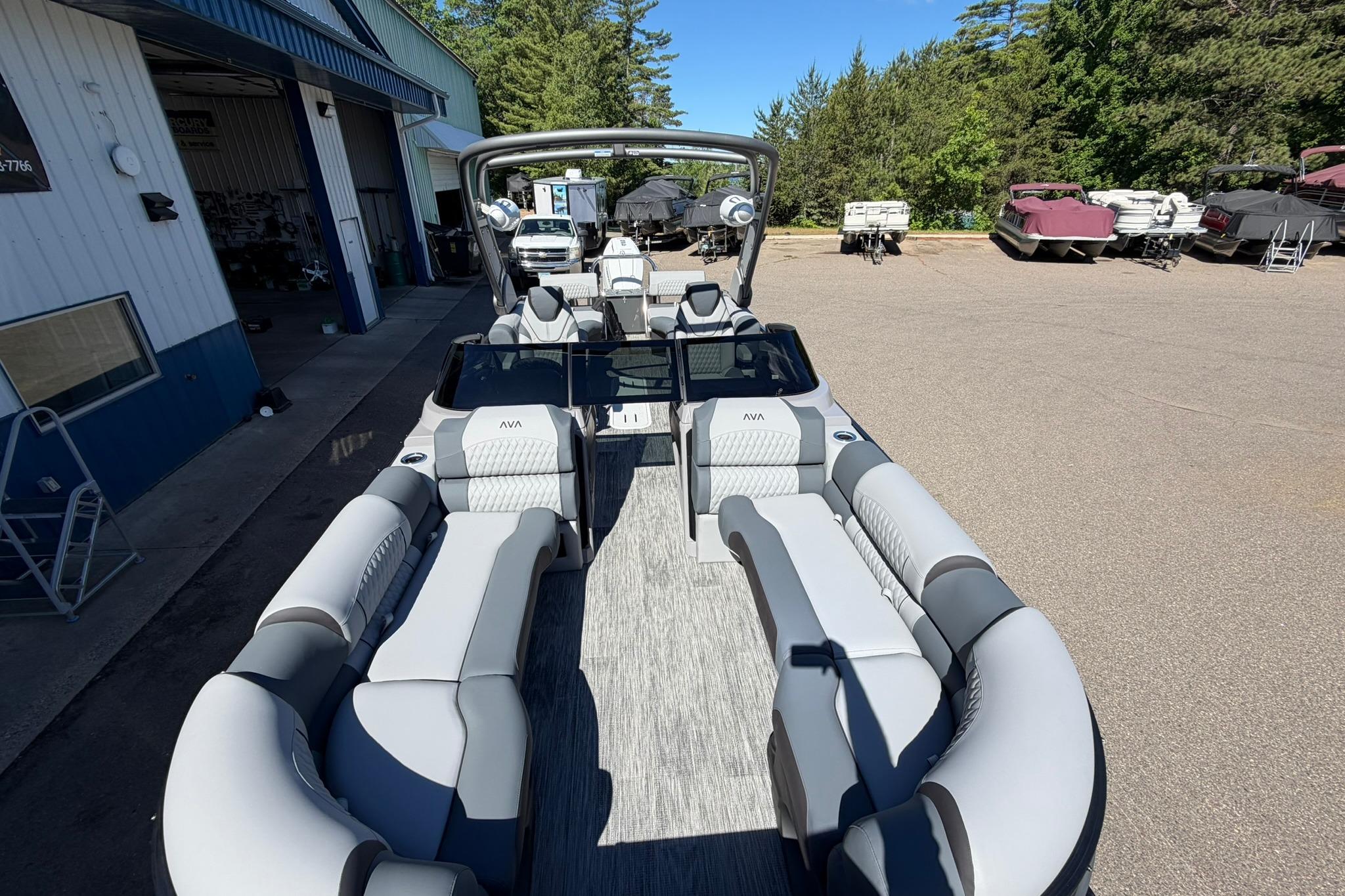 2026 Avalon Excalibur LTD Quad Lounge boat with windshield, parked outdoors near a building.