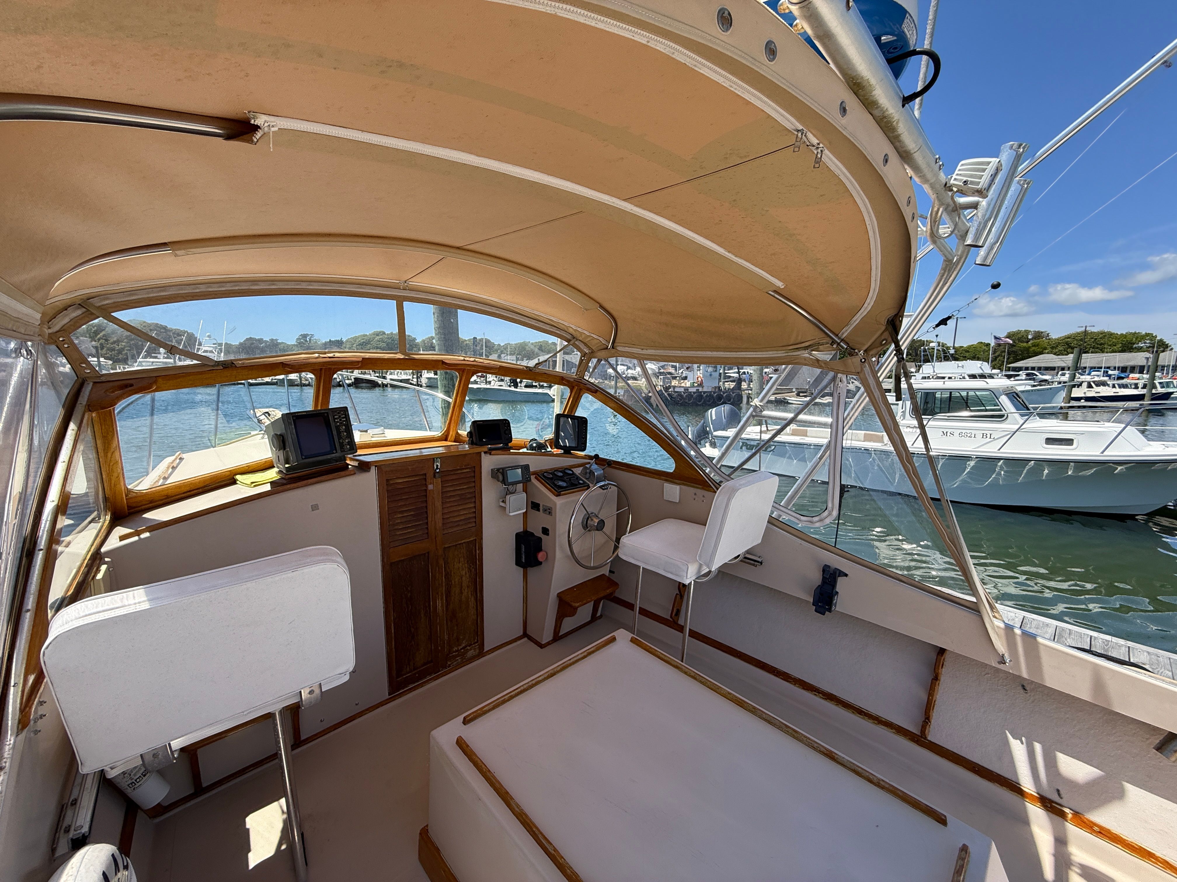 The cockpit of a 1989 Fortier 26 boat in a marina, featuring helm and seating.