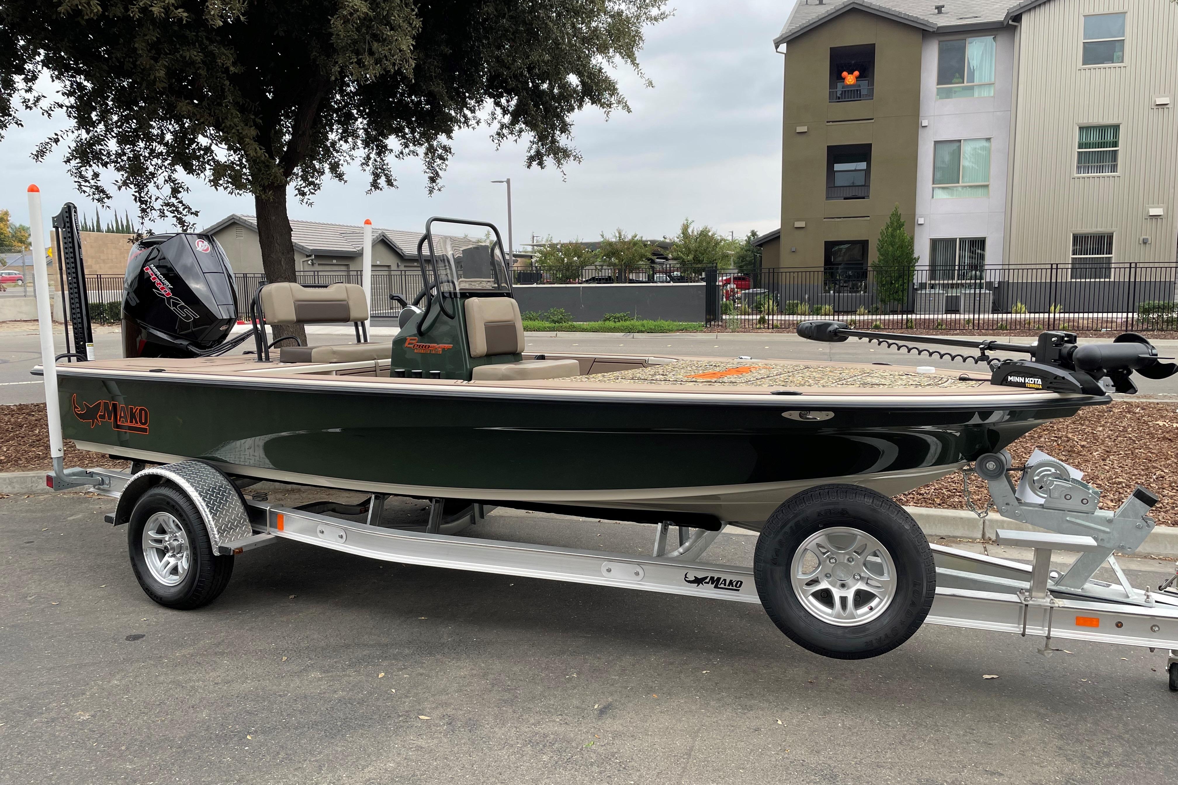 2025 Mako 18 Pro Skiff Backwater Edition boat on trailer, parked outdoors.