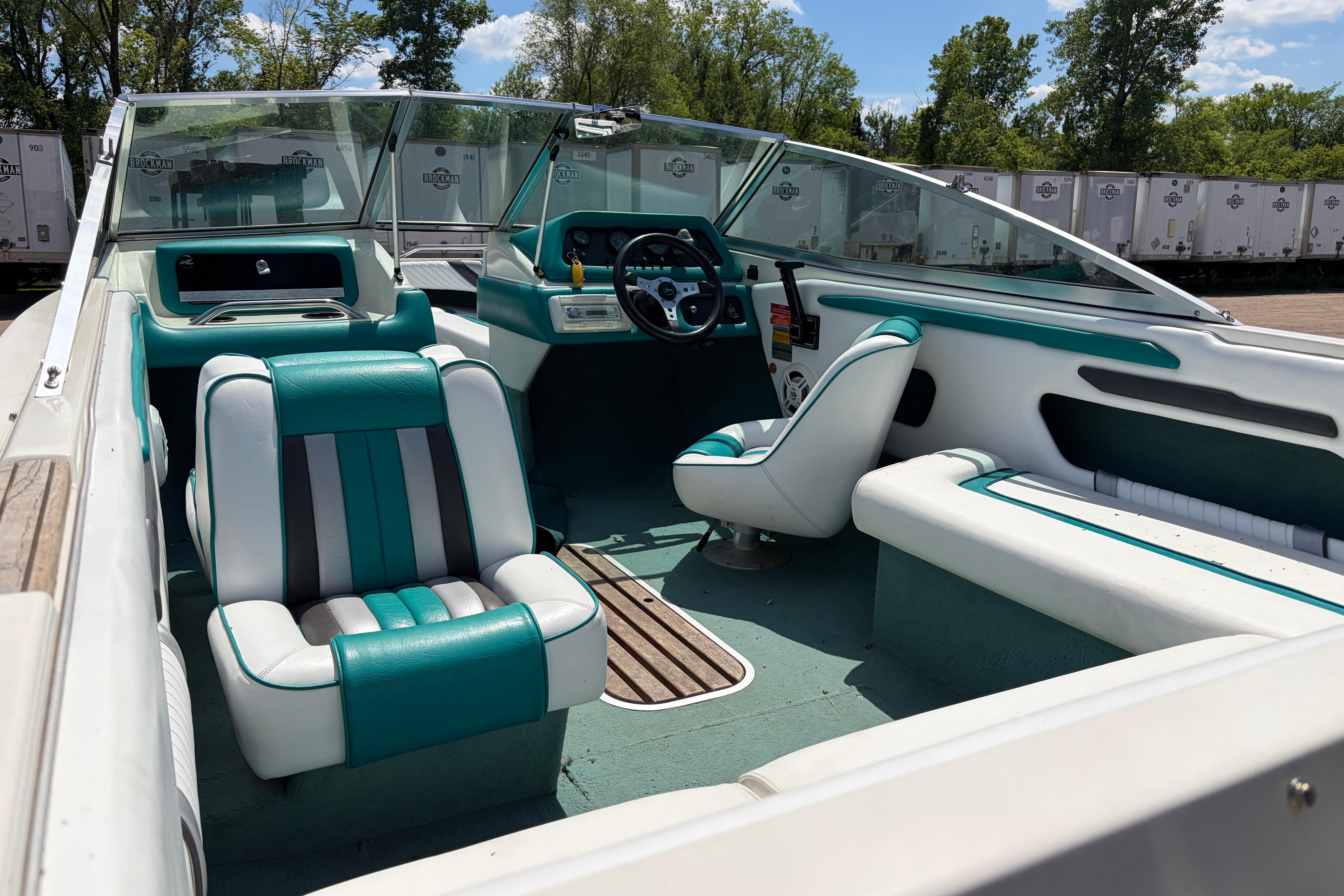 1990 Sea Ray 180 Bow Rider interior with teal and white seating, steering wheel, and dashboard.