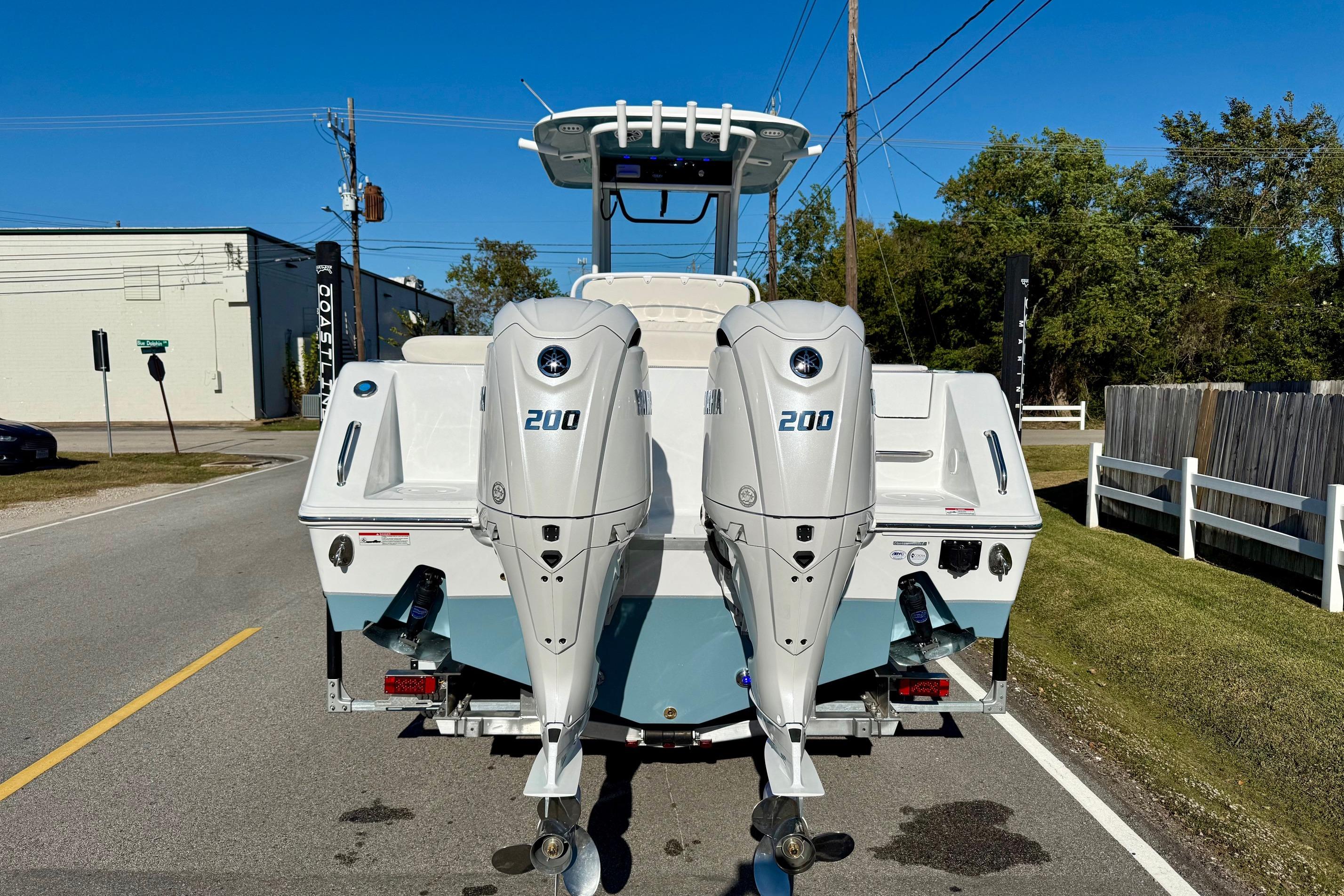 2026 Sea Hunt Ultra 275 Coffin Box boat with dual 200 horsepower engines on a sunny street.