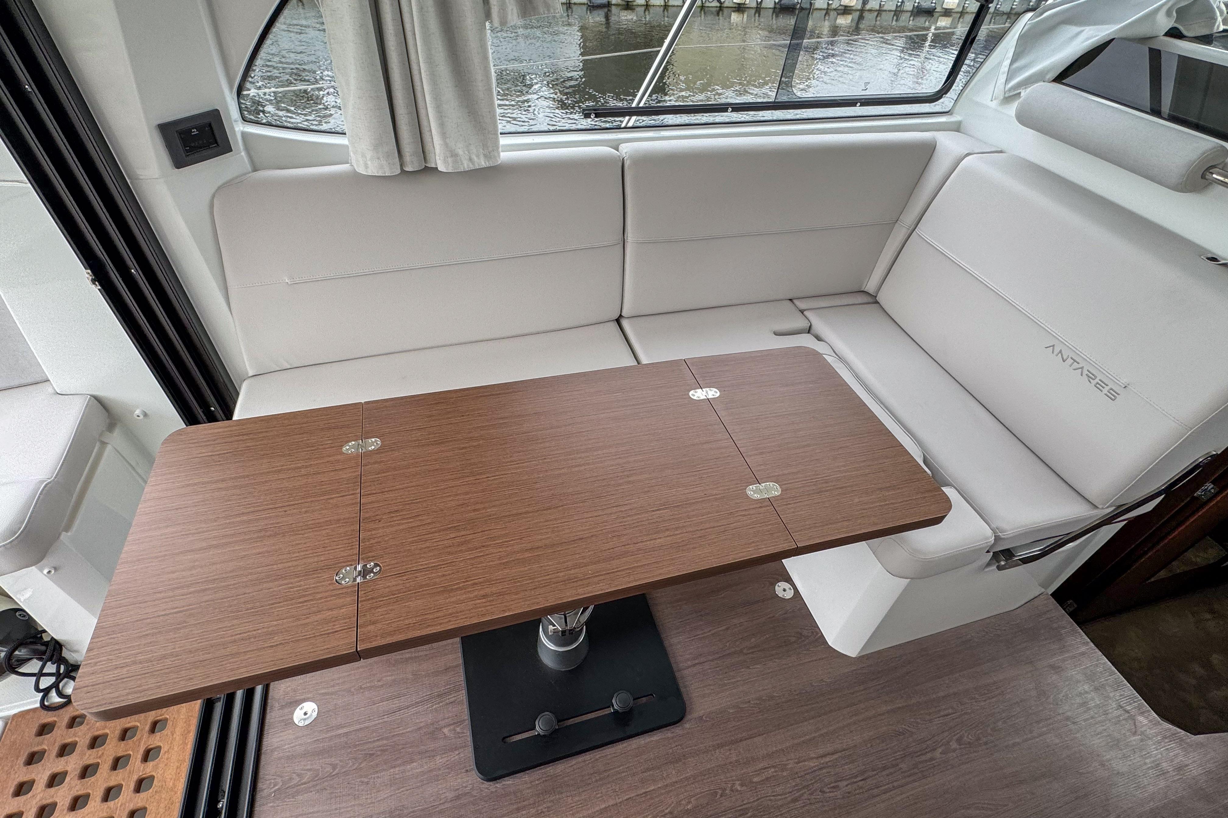 Interior of 2026 Beneteau Antares 11 with wooden table and white seating.