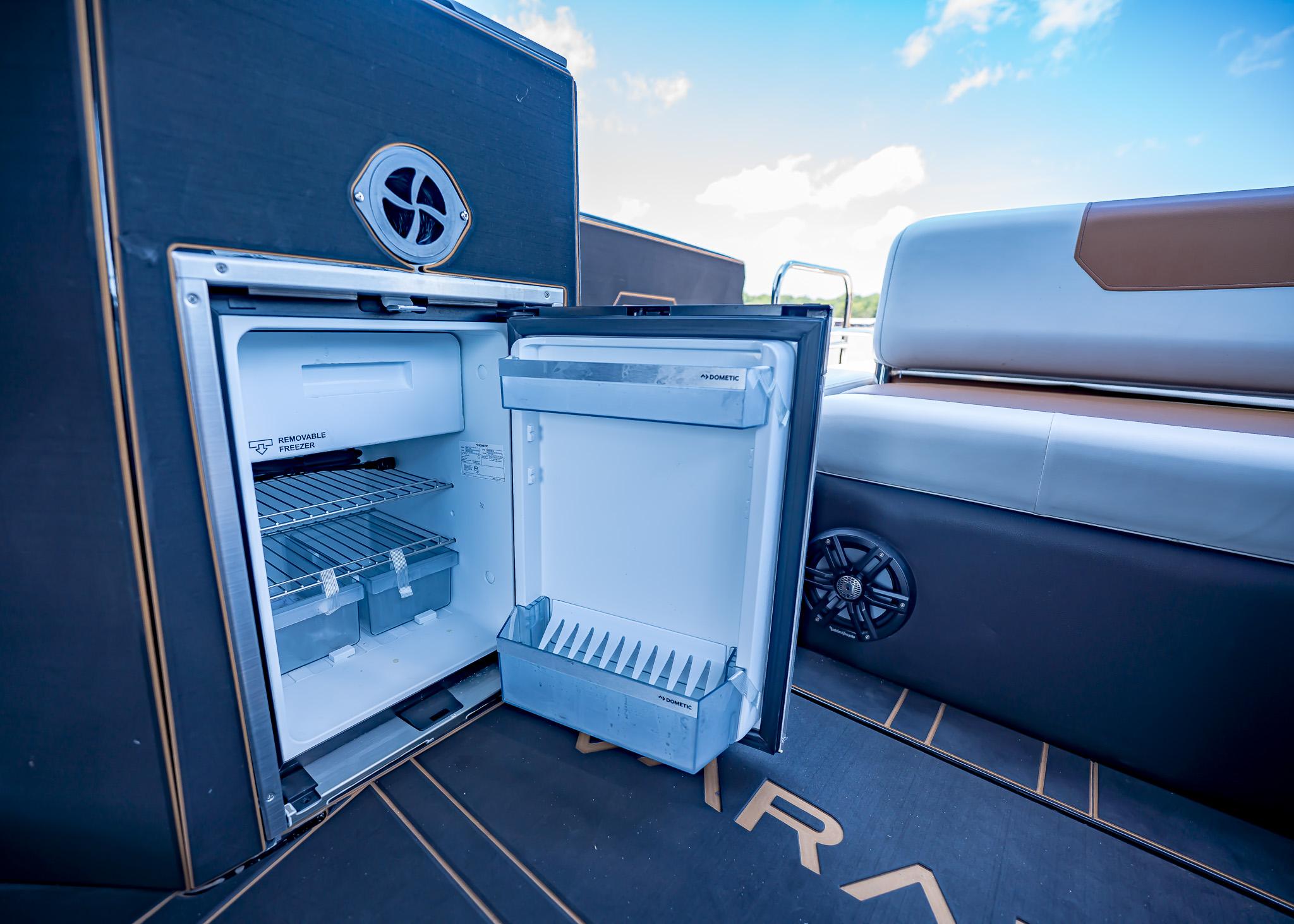 Open refrigerator on Paradigm 236 boat, showcasing interior storage and seating area, 2025 model.
