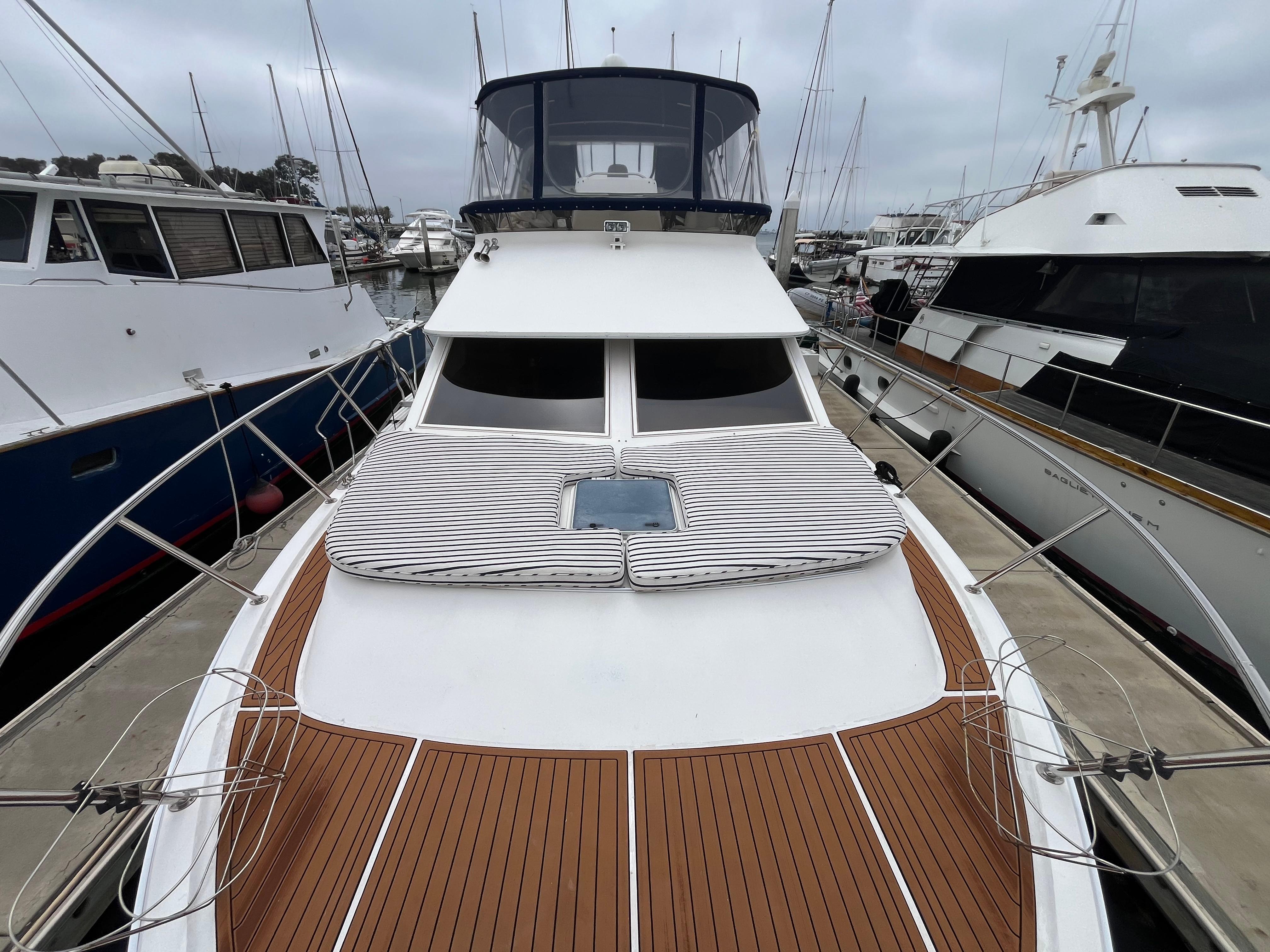 Ocean Alexander Sundeck 460, 1999 model, docked with teak deck and striped sun pads.