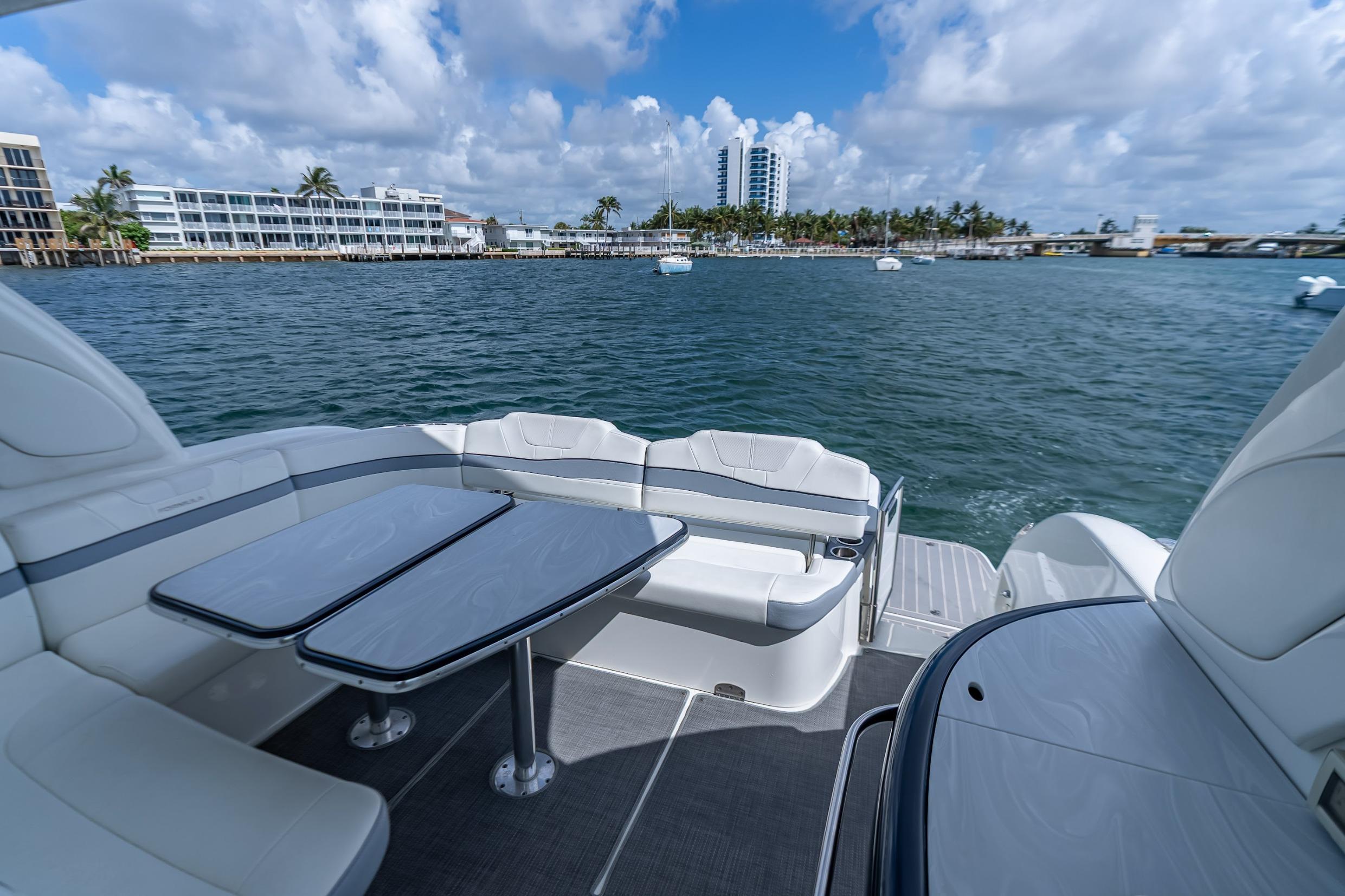 2022 Formula 40 Performance Cruiser deck with seating and tables, overlooking a scenic waterfront.