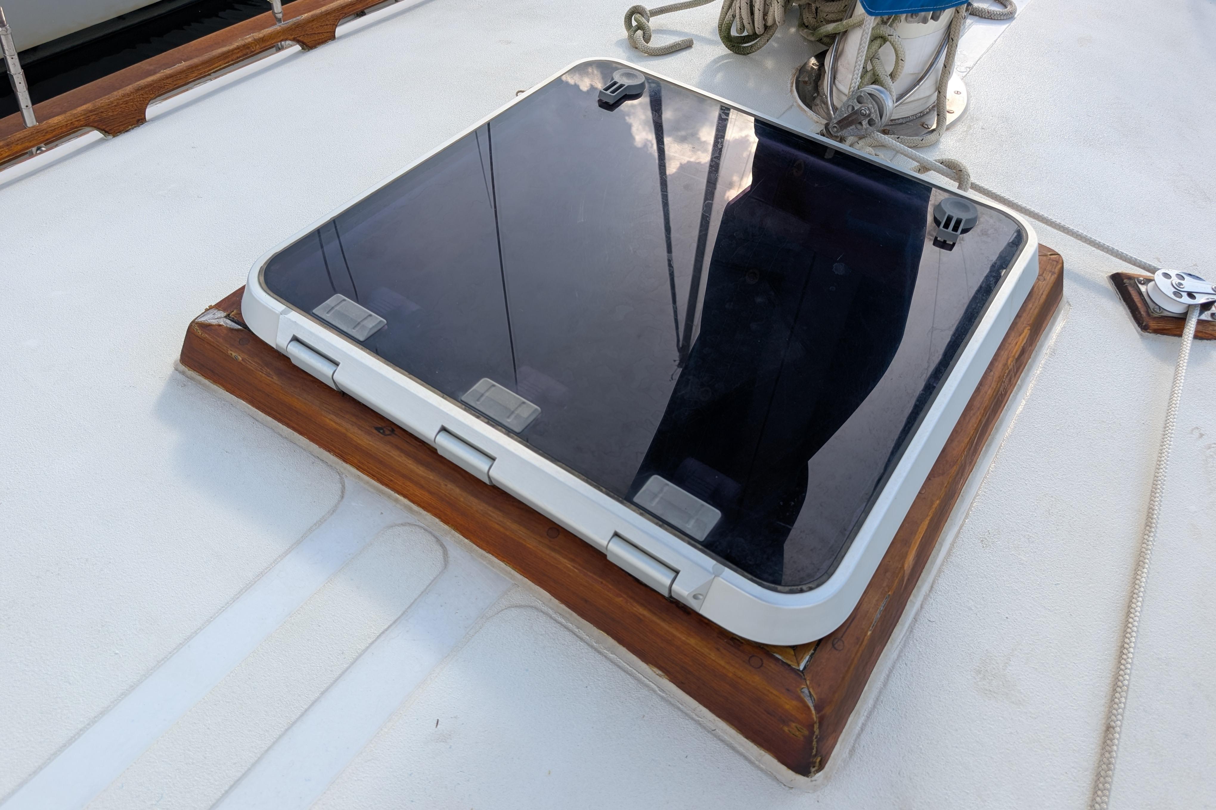 Hatch on 1983 Robert Perry 41 sailboat deck, featuring wooden trim and reflective surface.