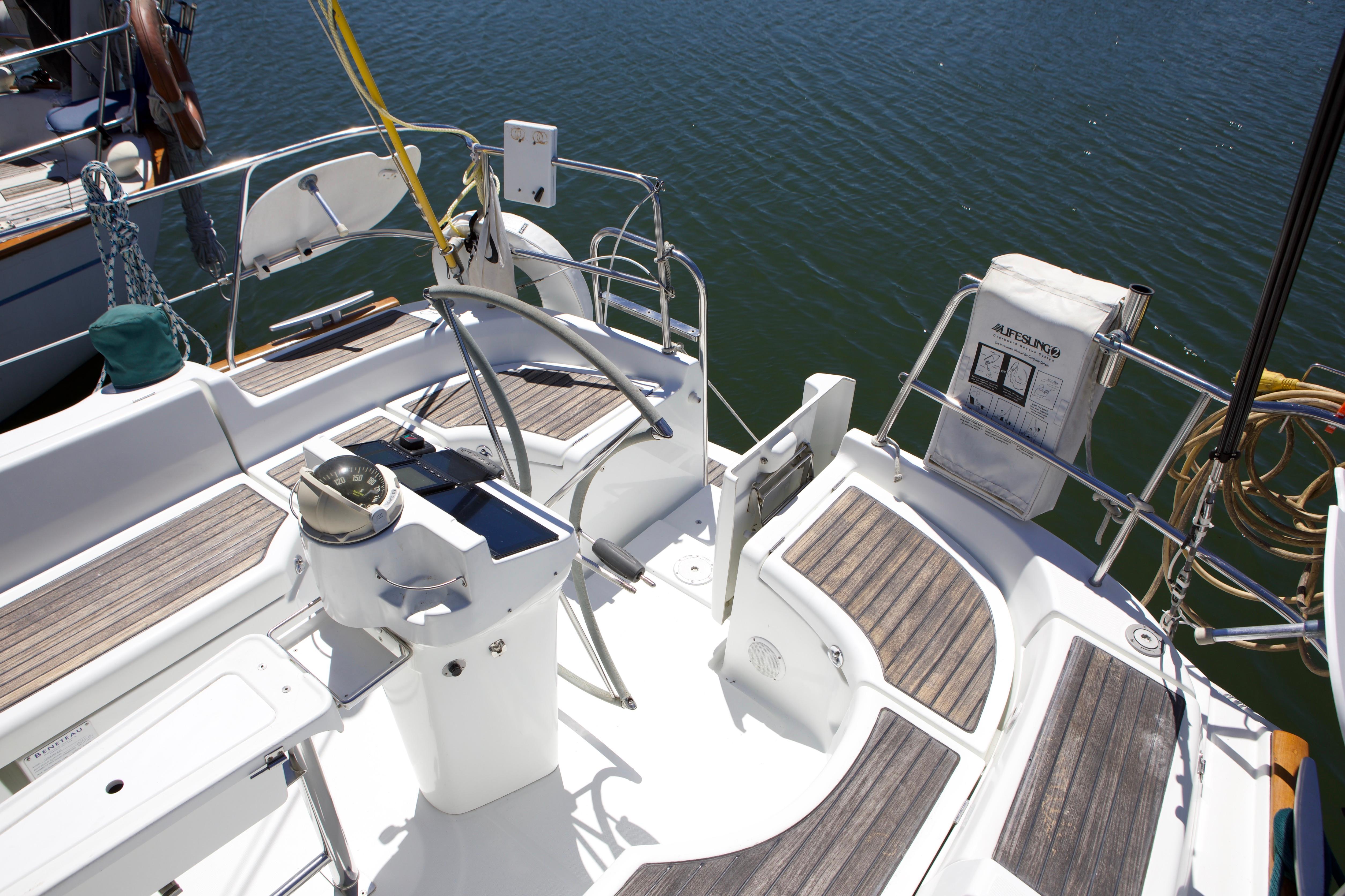 Cockpit of a 2005 Beneteau 423 sailboat with wooden seating and navigational equipment.