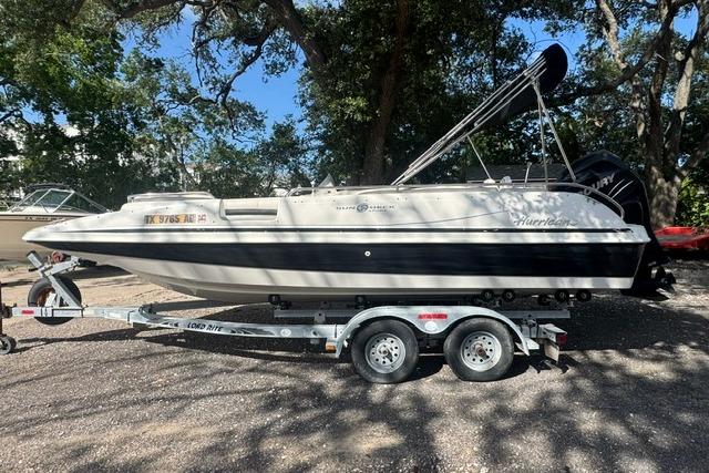 1999 Hurricane SunDeck Sport 201 OB boat on trailer, parked outdoors.