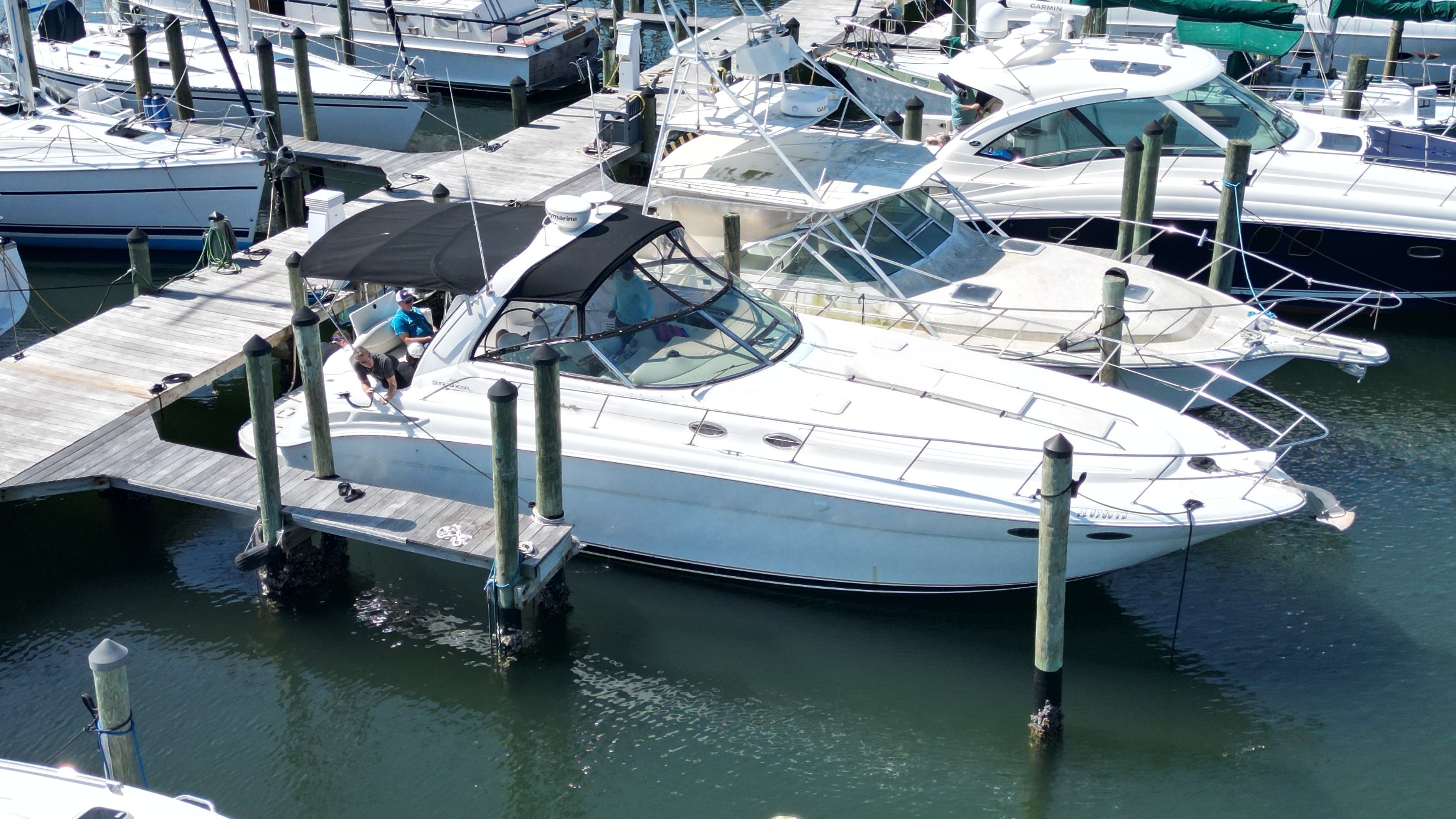 A white motorboat is docked in a marina, surrounded by other boats.