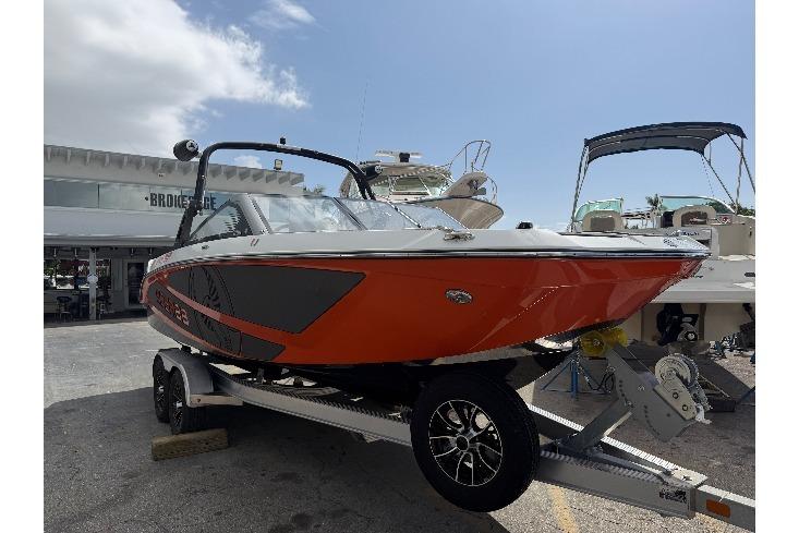 2026 Scarab 235 LX boat on trailer, vibrant orange and black design, parked outdoors.