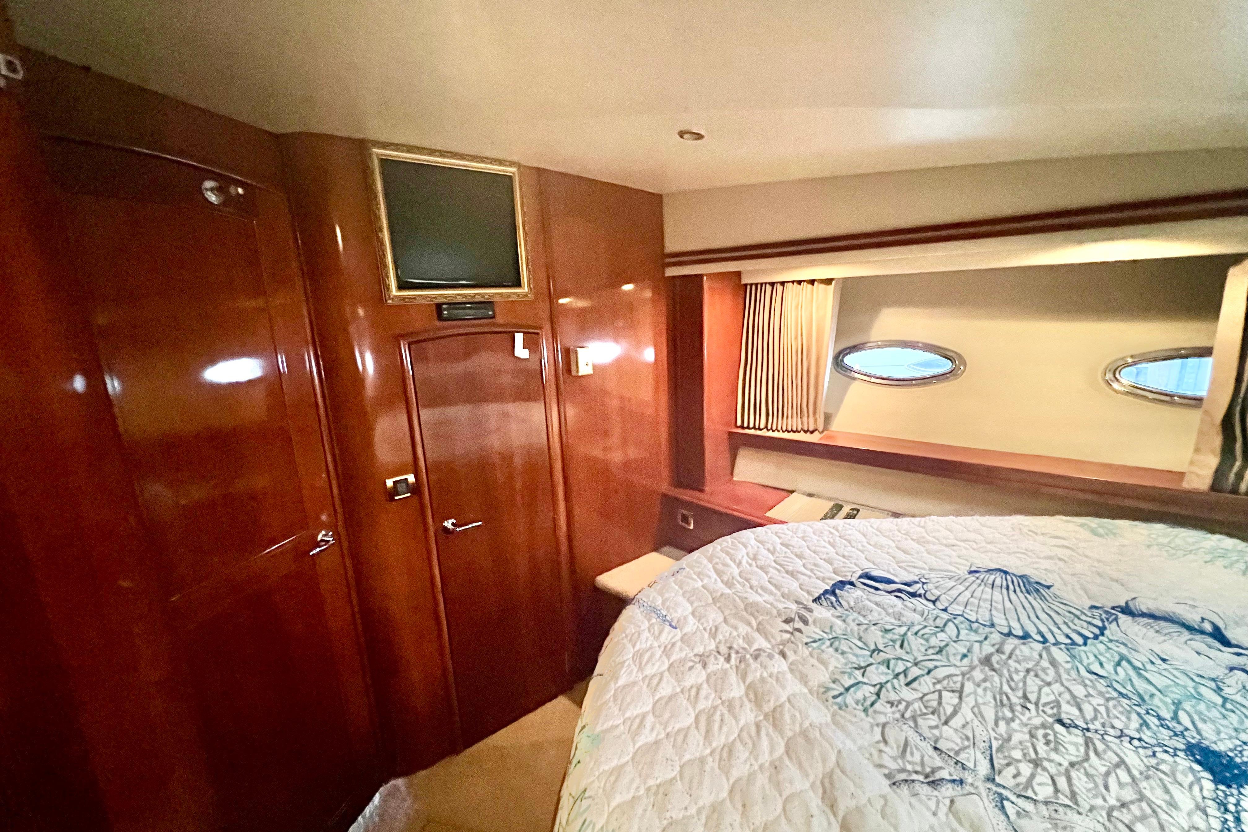 Luxurious 2005 Carver 56 Voyager yacht bedroom with elegant wood paneling and cozy bedding.